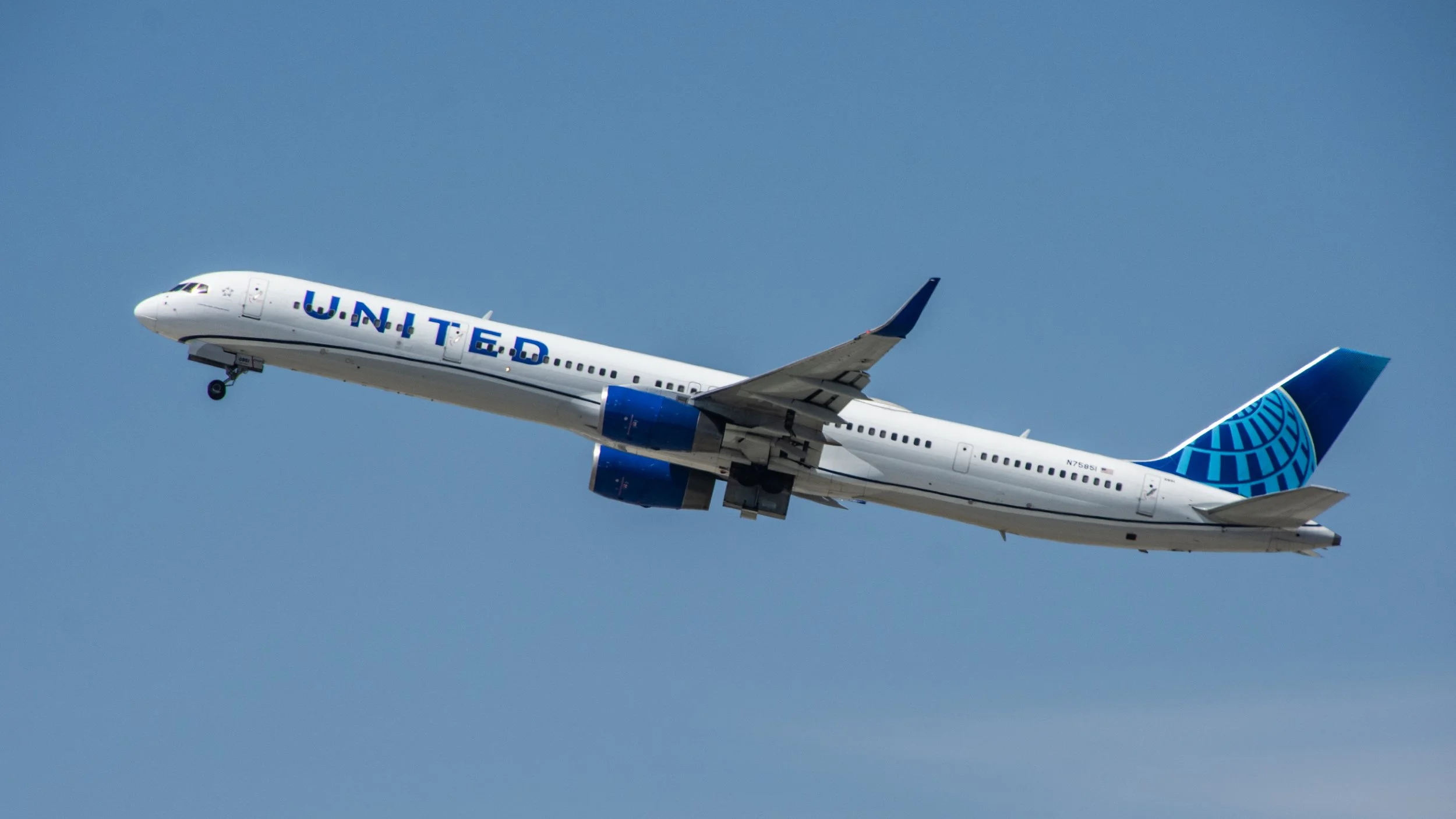 United Airlines Boeing airplane in flight against blue sky.
