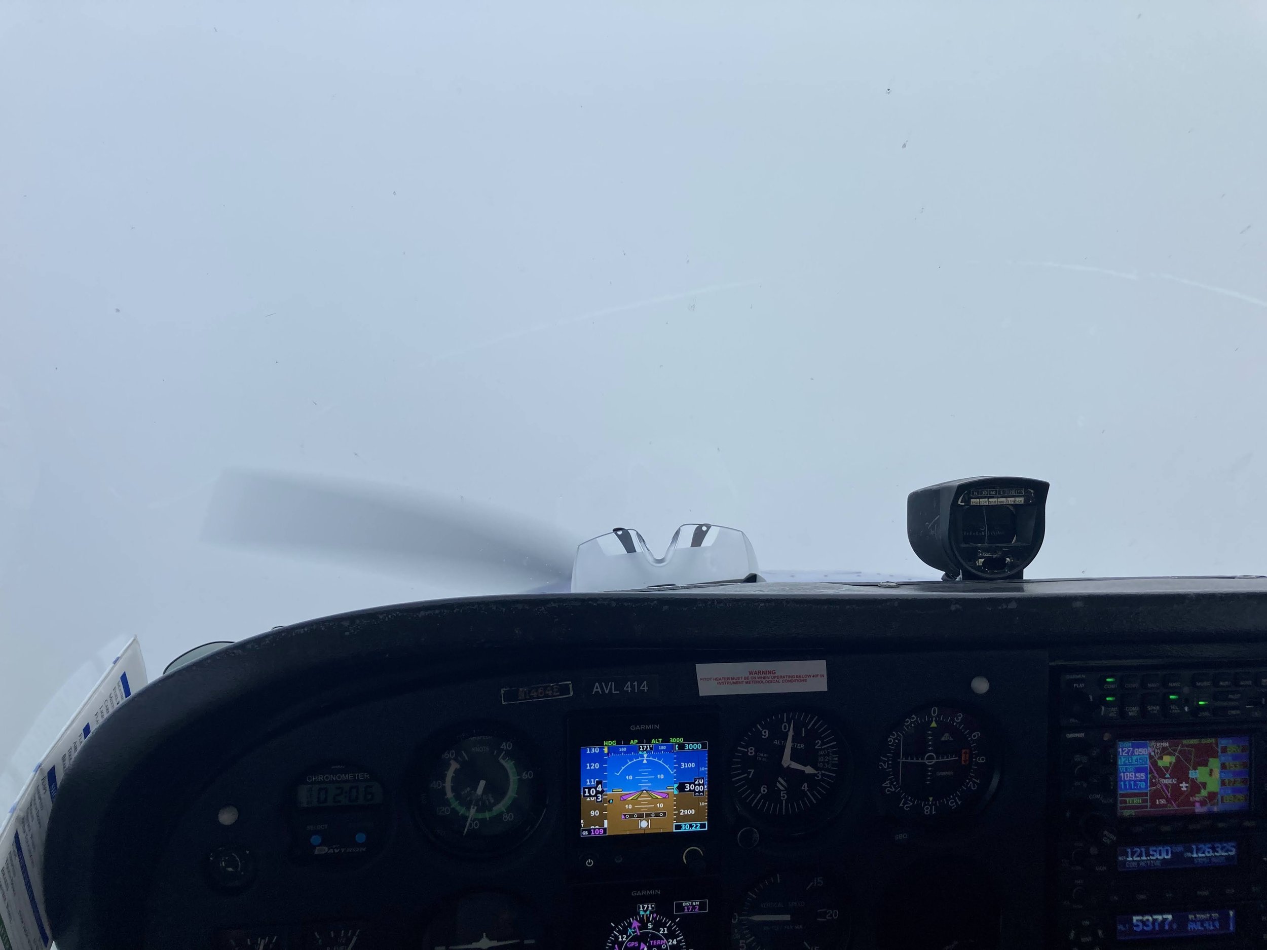 View of an aircraft cockpit with multiple instruments and screens, showing navigation and altitude information, with a clear sky outside.