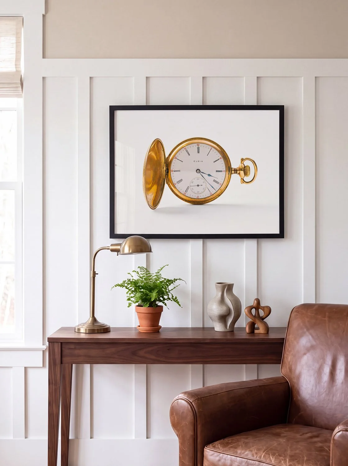 Framed fine art print of a 1908 Elgin gold pocket watch hanging above a walnut console table