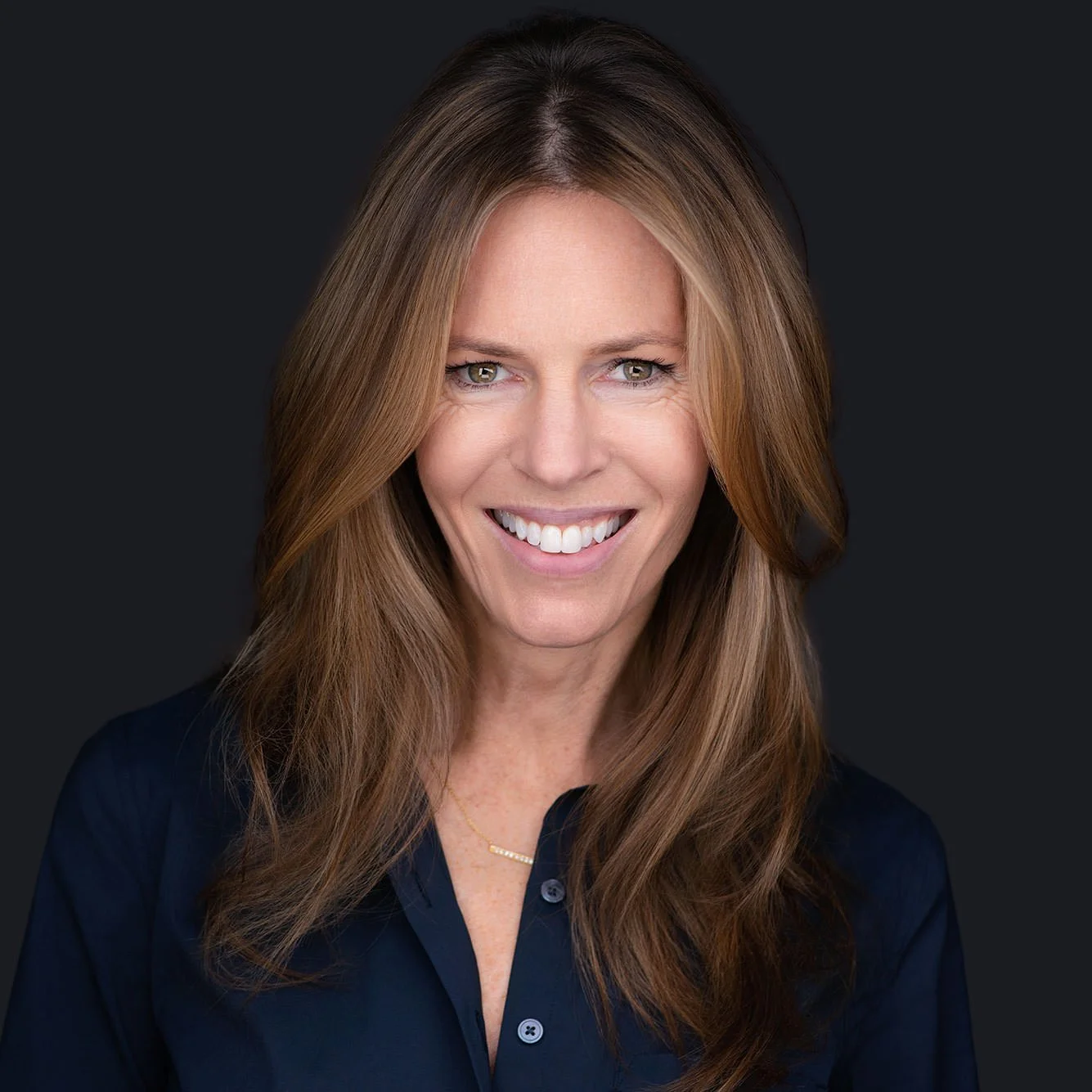 female in blue button shirt smiling brightly for the camera