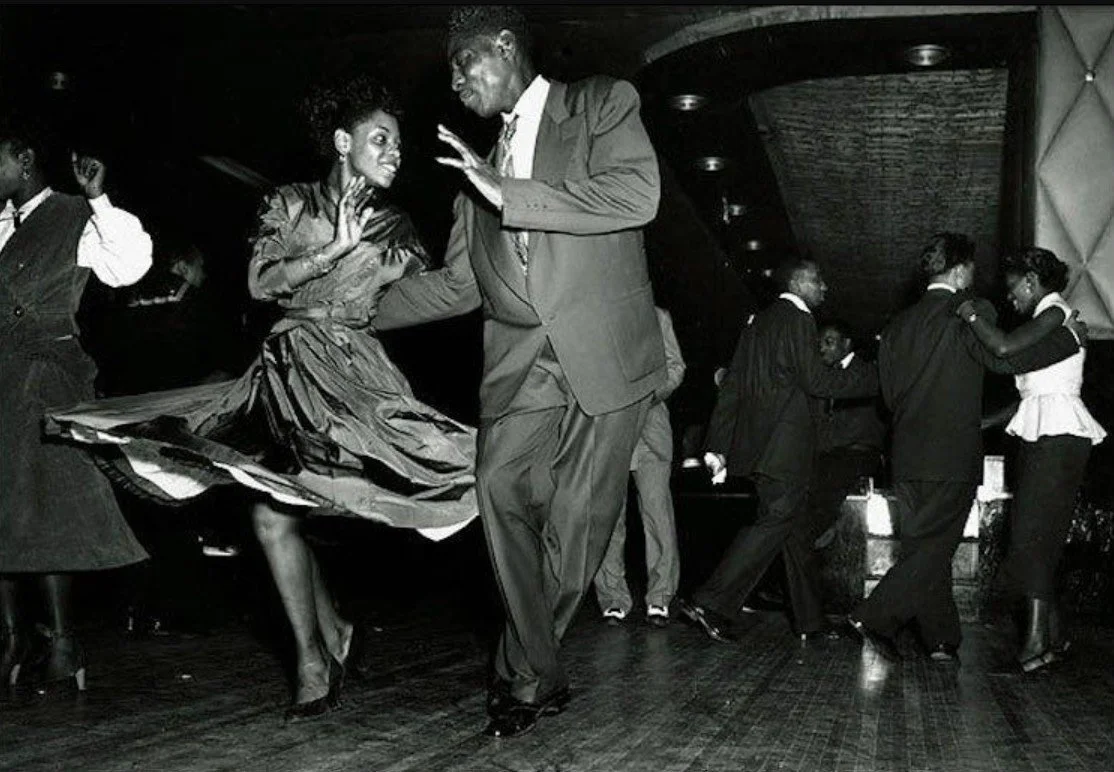 Mennesker som danser på en nattklubb, svart-hvitt bilde, man og kvinne i midten som danser sammen.