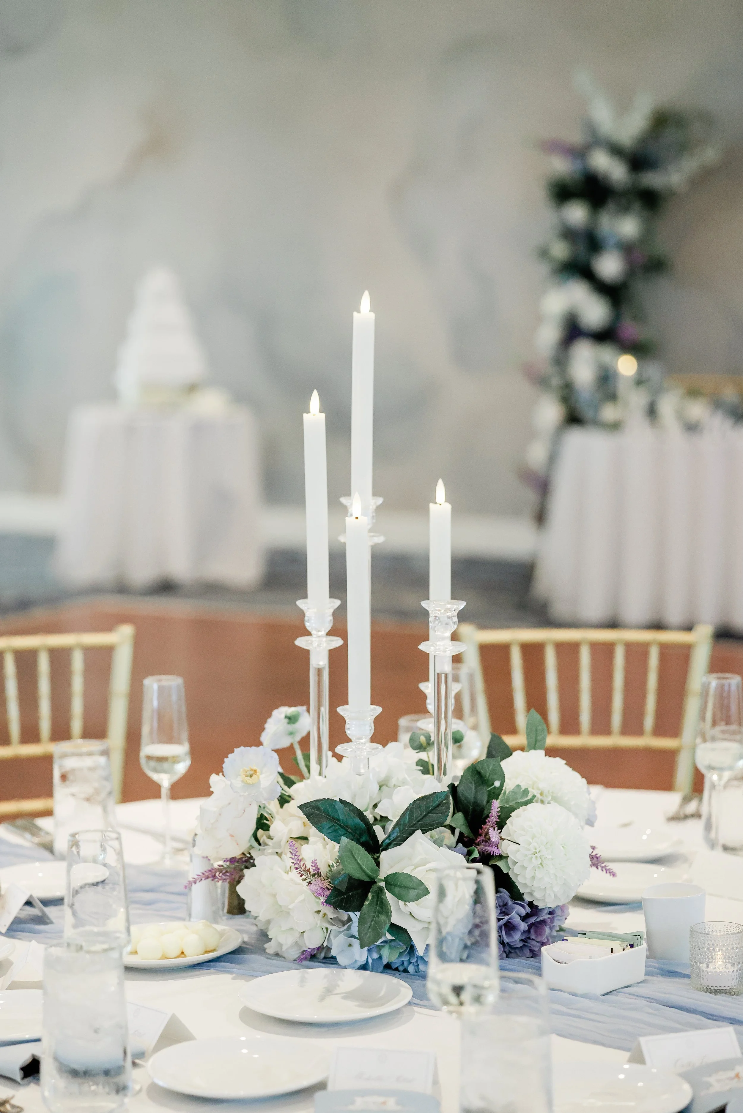 Elegant table setting with white candles and floral centerpiece at a formal event.