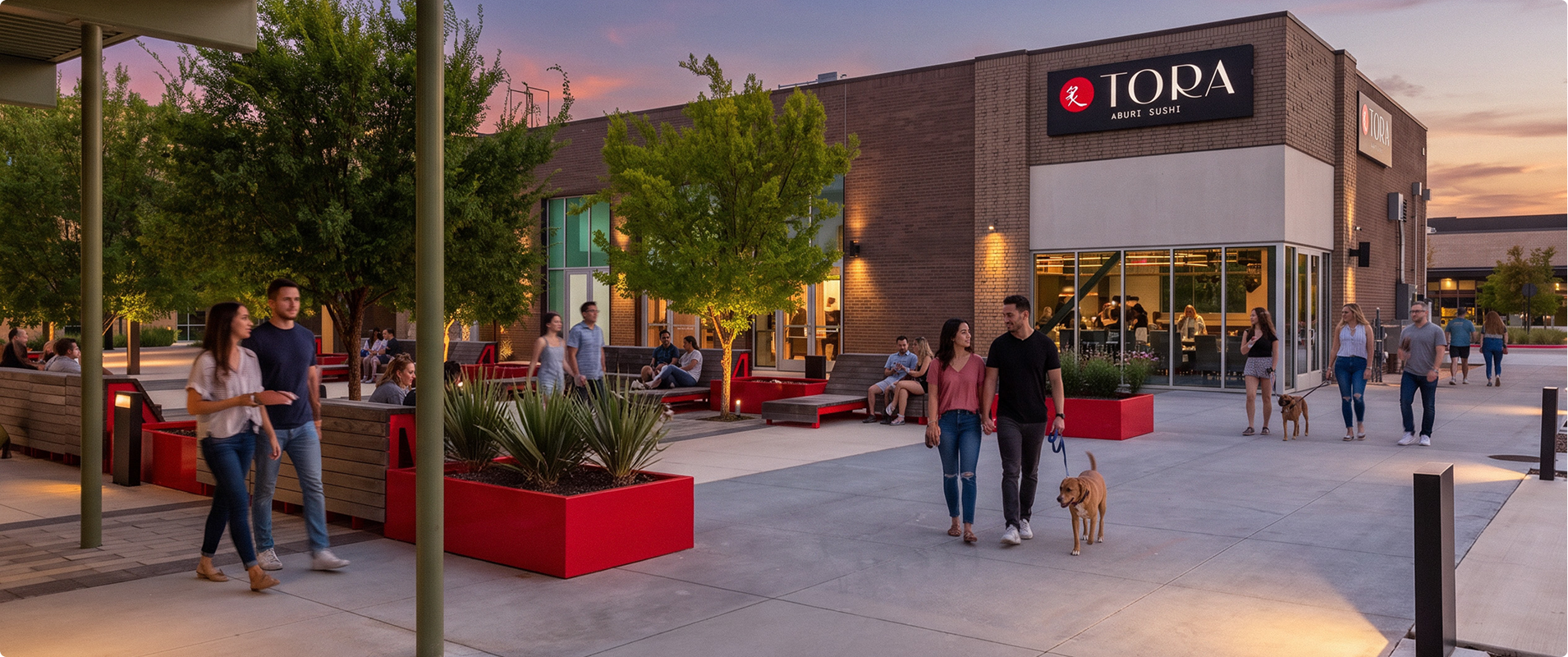 People walking and sitting outside a modern restaurant named Tora Aburi Sushi during sunset, with trees, benches, and red planters in a shopping plaza.
