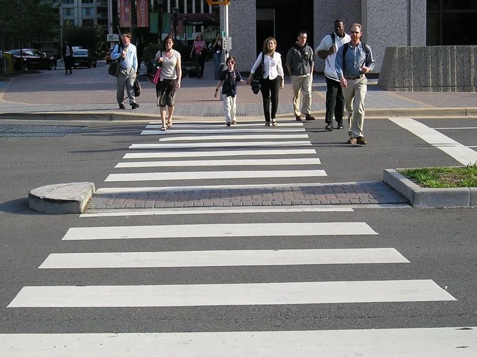 People crossing the street at a crosswalk in an urban area.