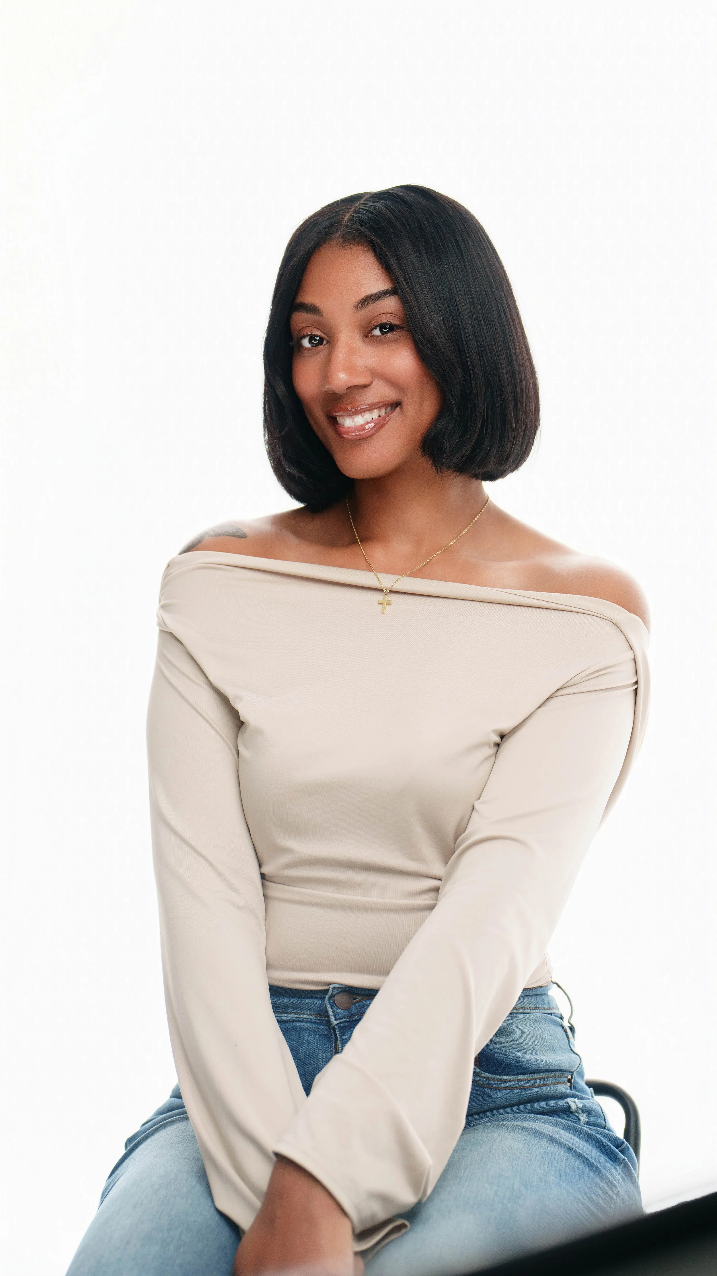 Imani Love, founder of Love Luxury, wearing a straight black bob with raw hair and cream off-the-shoulder top, Kansas City natural hair stylist.