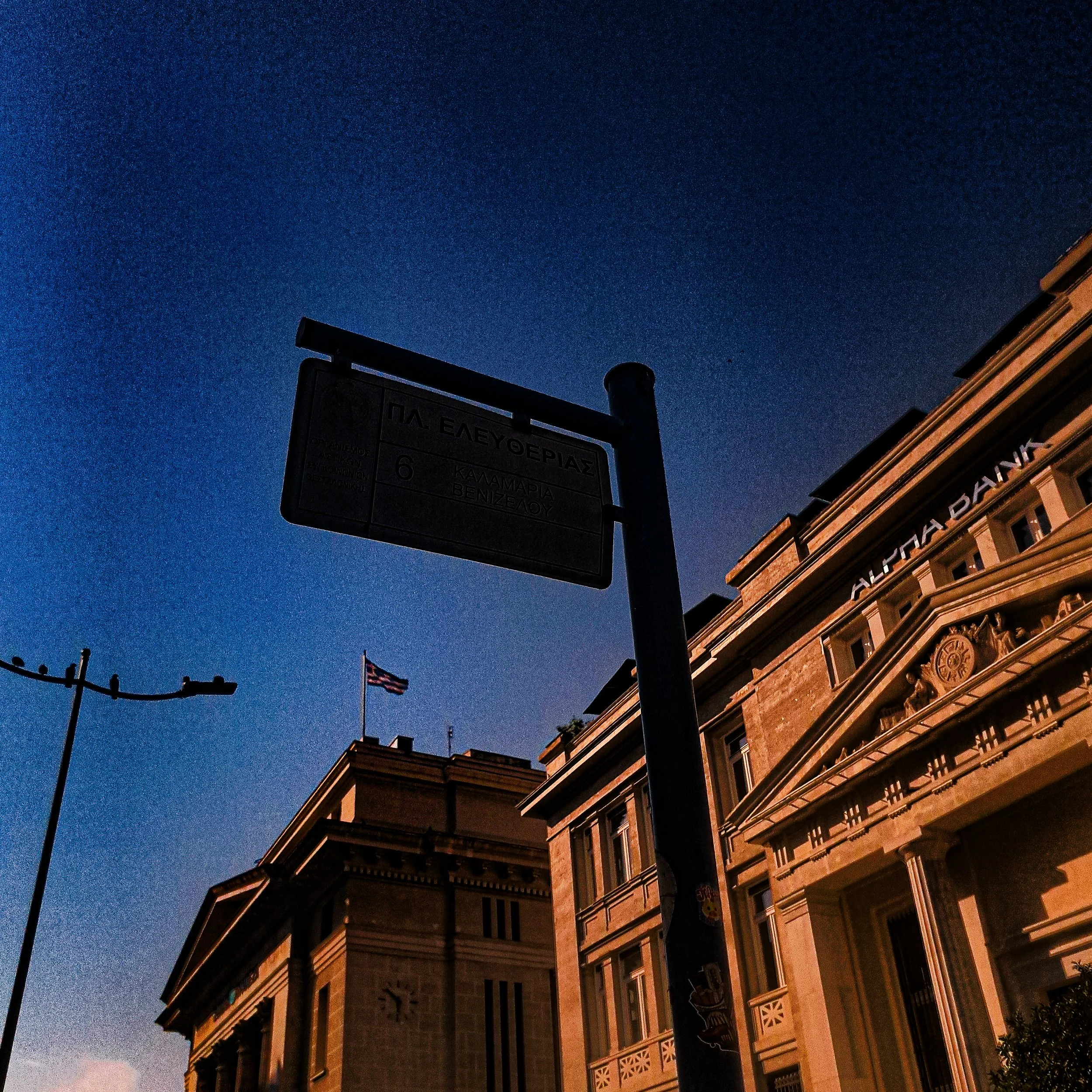 Nighttime view of a historic building with decorative architecture, illuminated by warm lights, and a dark blue sky overhead with a few clouds.