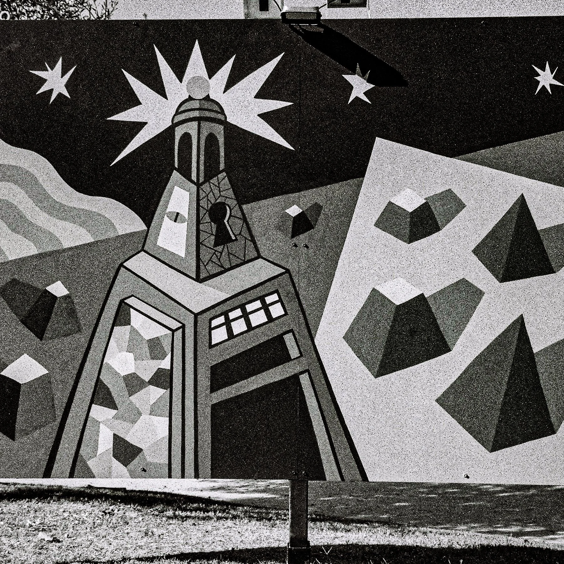 A mural painting on an interior wall featuring geometric shapes and celestial motifs, including stars and a lighthouse, rendered in black, white, and gray tones.