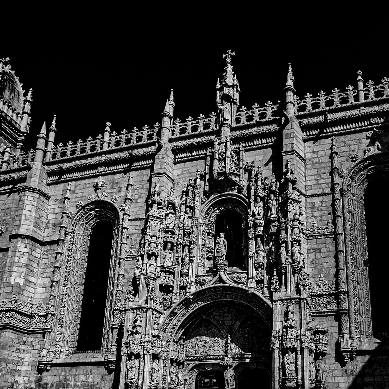 Black and white photo of a gothic cathedral front with detailed sculptures and pointed arches.