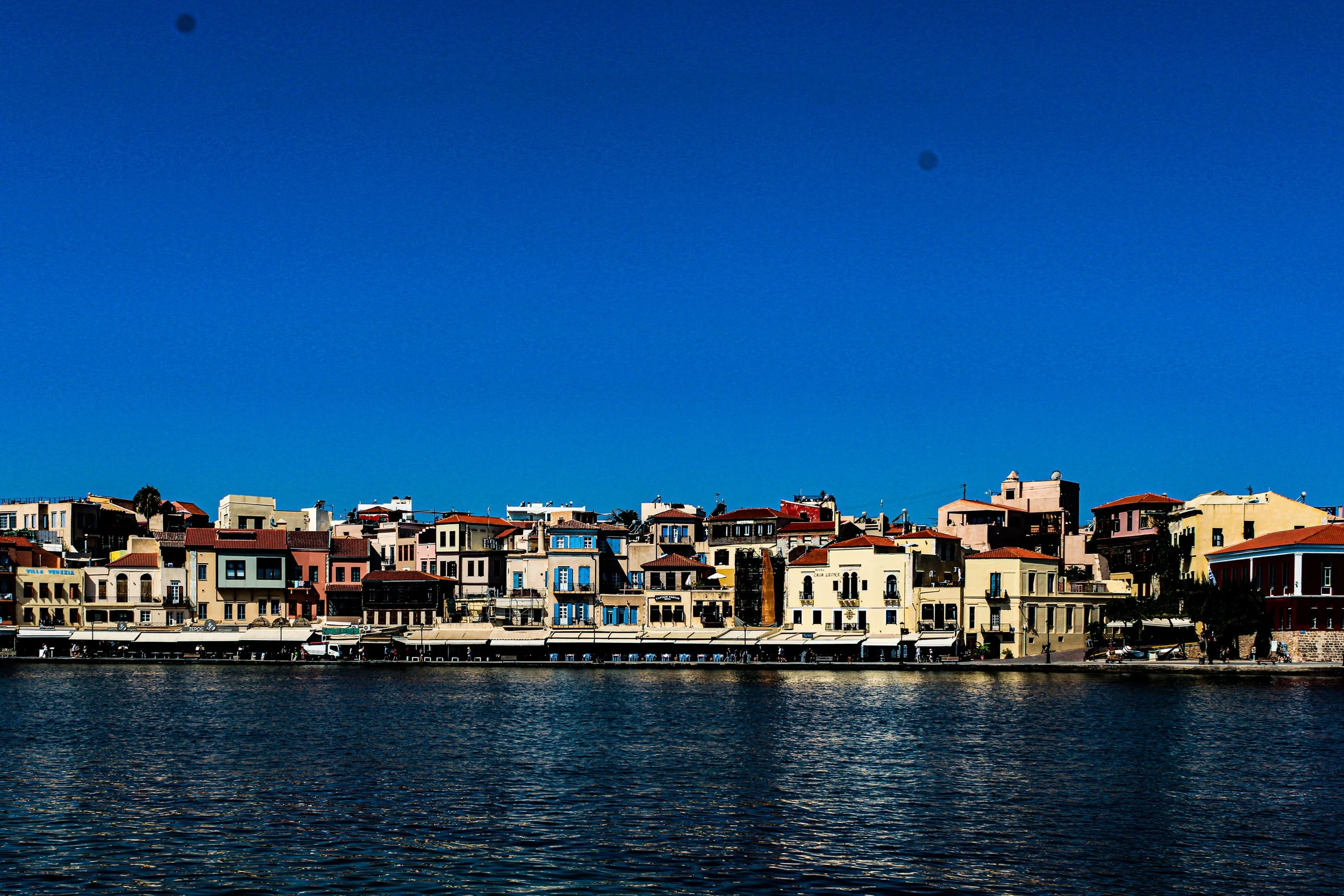 Colorful buildings along a waterfront under a bright blue sky.