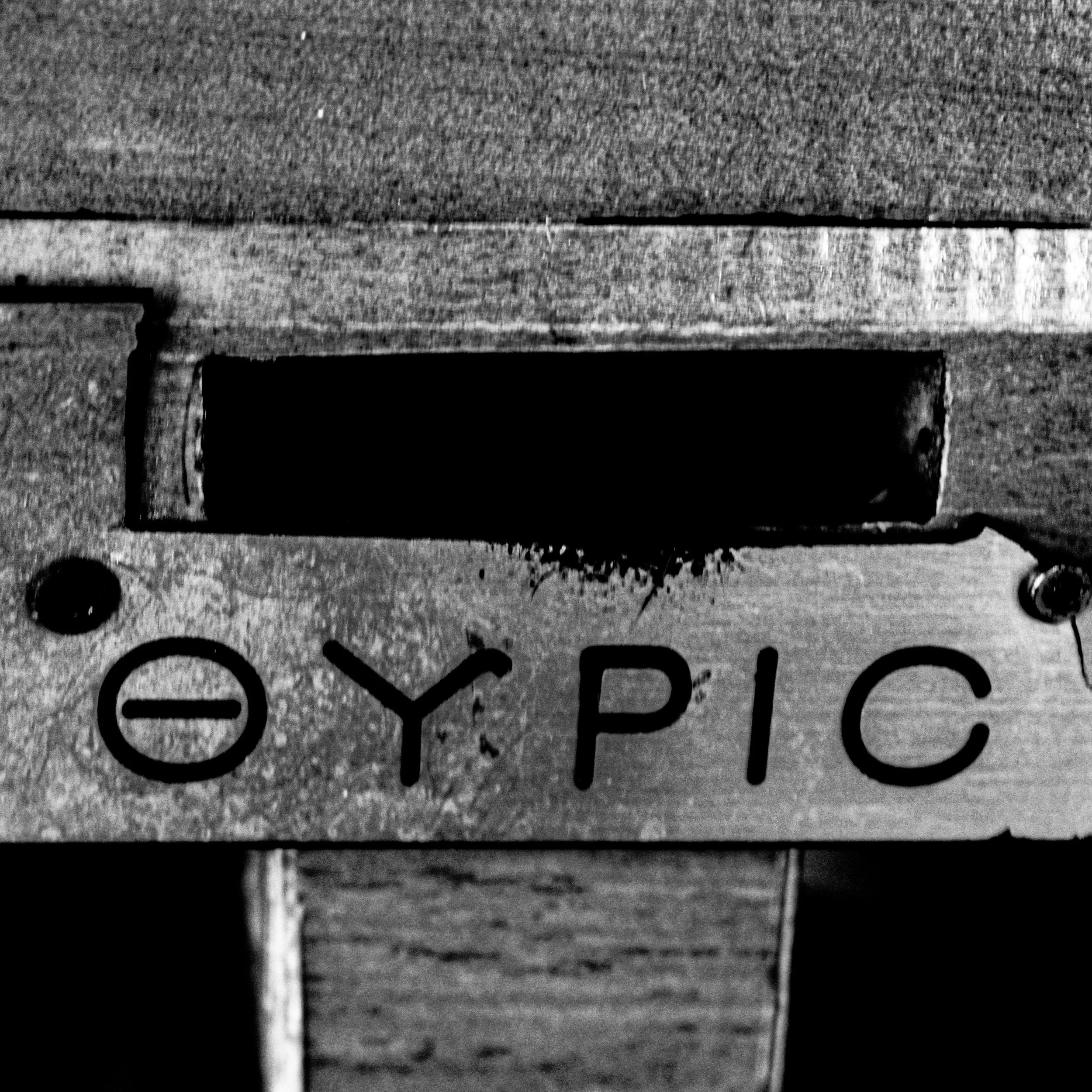 Close-up of a wooden surface with painted black text, part of a sign or label.