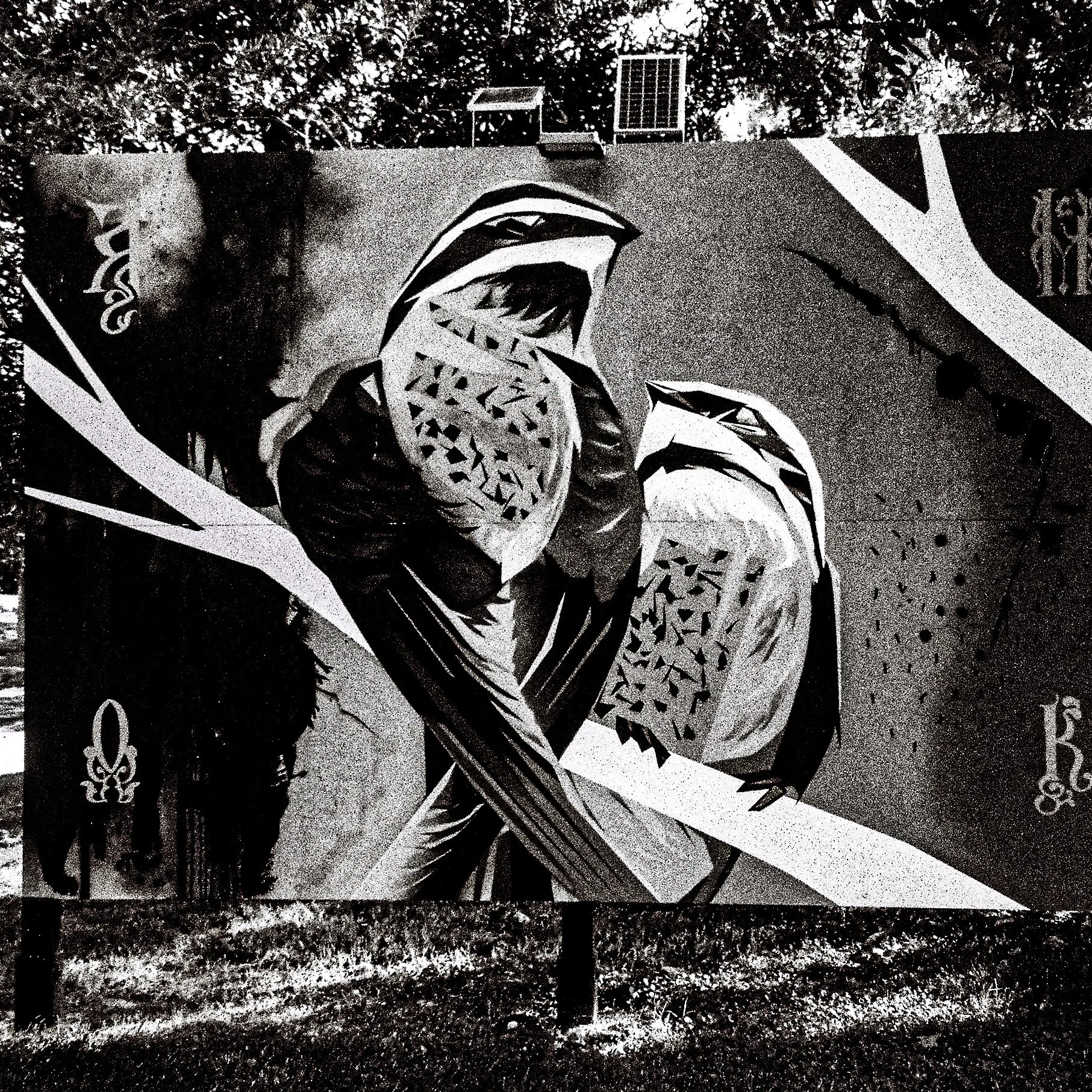 Black and white graffiti mural of a roaring animal, possibly a wolf or a bear, with intricate details on its face, surrounded by abstract shapes and floral patterns, painted on an outdoor wall.