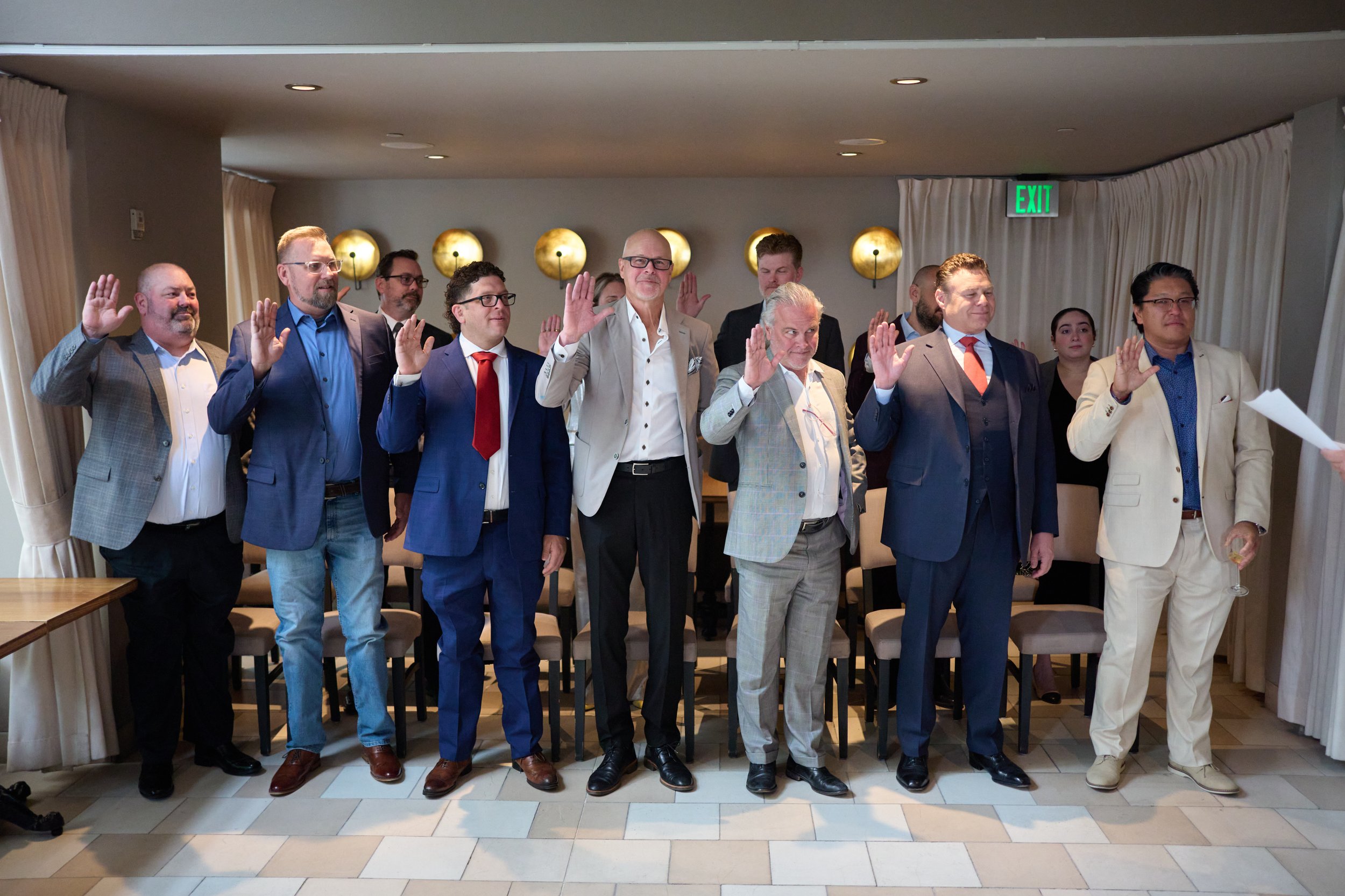 Group of diverse professionals standing in a line in a conference room, raising their right hands in a swearing-in or oath-taking ceremony.