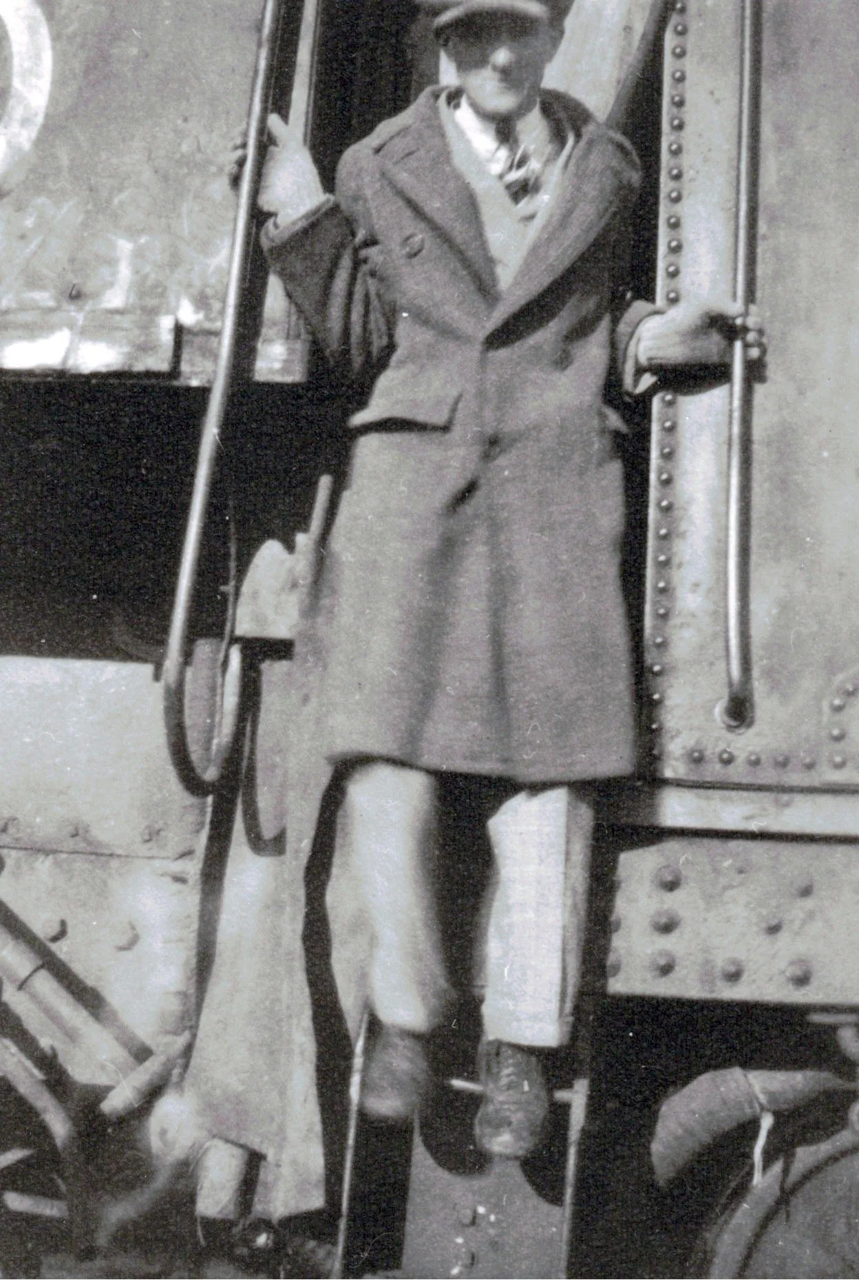 A black-and-white photo of a man in a heavy coat, jumping off a train in Canada