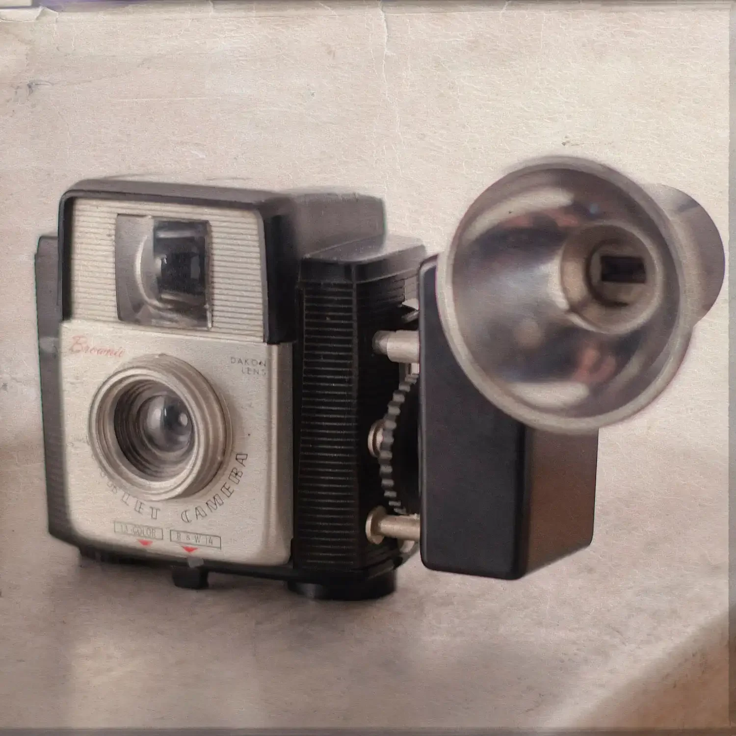 A vintage Kodak film camera with a metal body and a large lens, positioned on a flat surface.