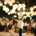 People dancing at a party under hanging string lights.