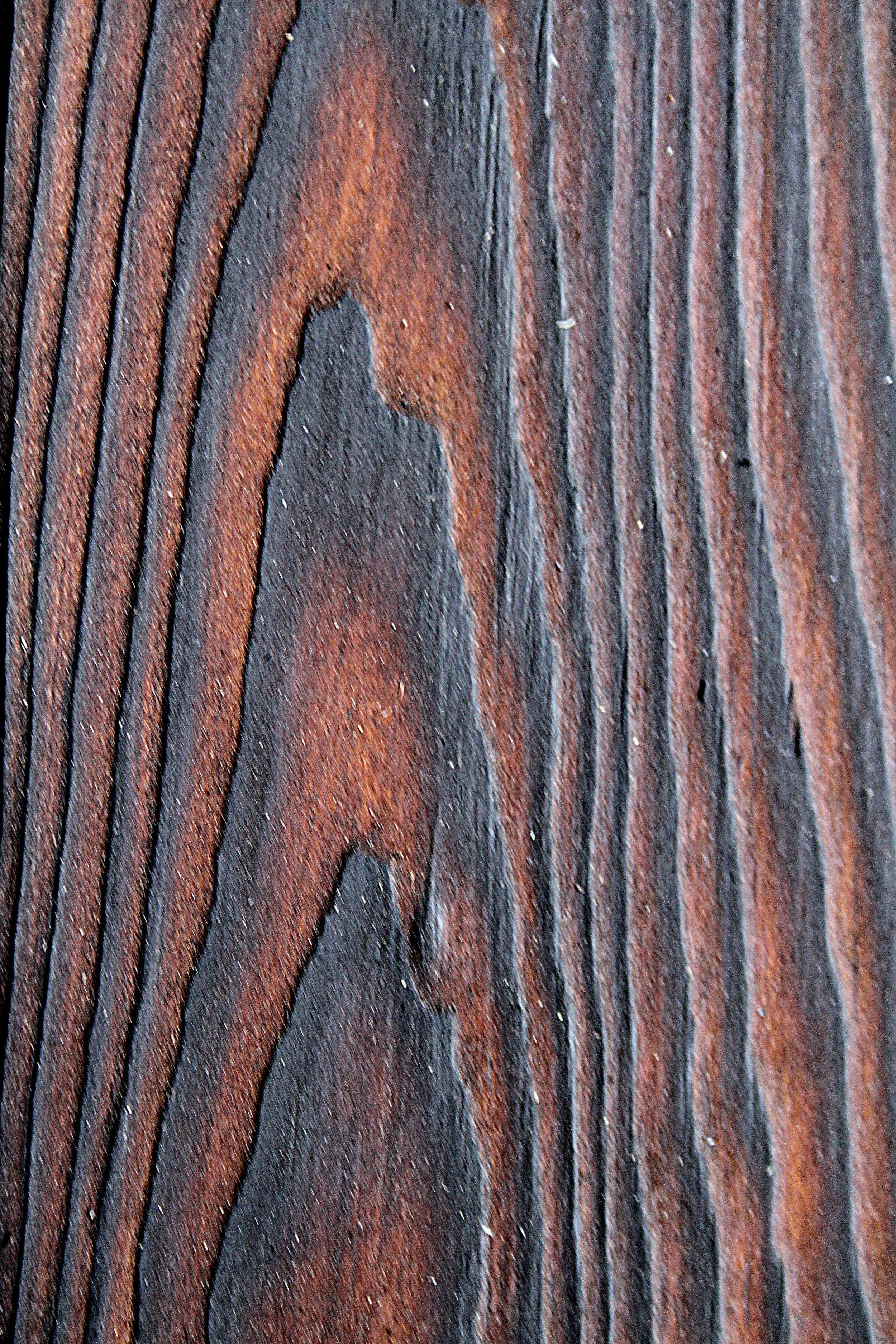 Nahaufnahme eines Holzbretts mit horizontalen schwarzen und braunen Streifen.