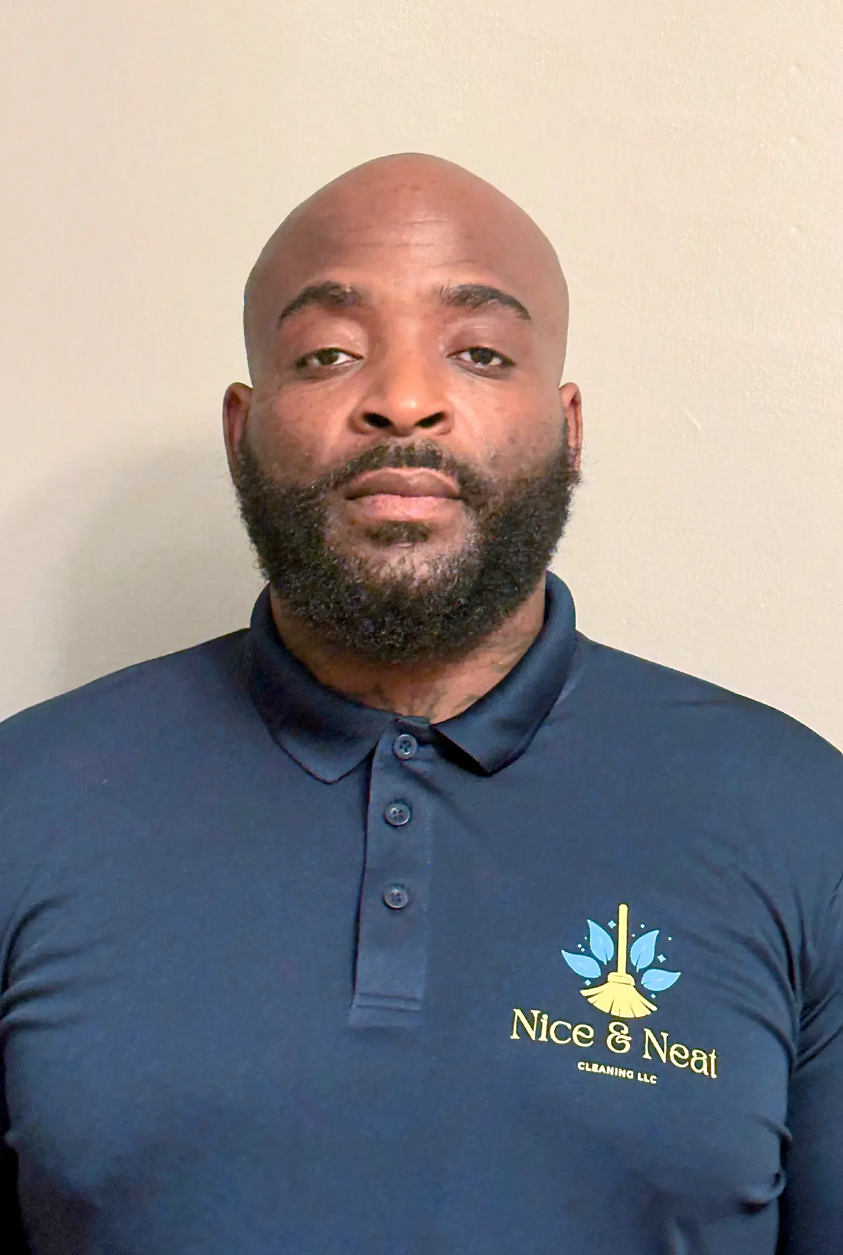A man with a goatee wearing a navy blue polo shirt with a logo that reads "Nice & Neat Cleaning, LLC."