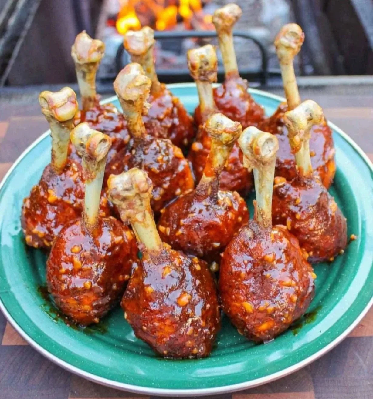 Meatballs on a plate covered in red sauce with baked chicken drumsticks with bones in a bowl