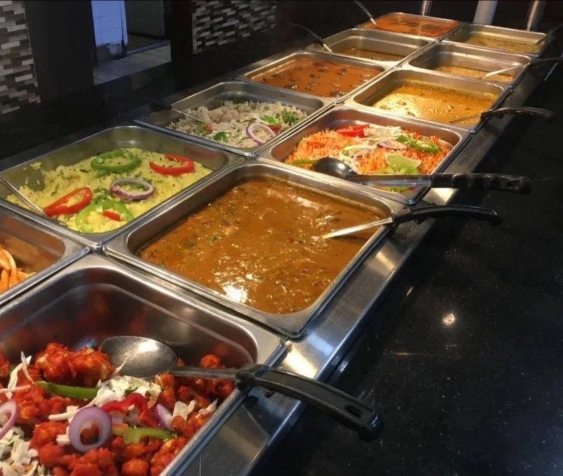 A buffet spread with various Indian dishes including curries, rice, and vegetarian options.