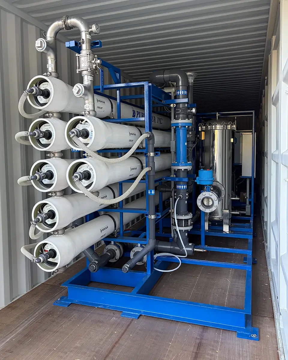 Industrial water filtration system with multiple filtration cylinders, pipes, and valves inside a metal enclosure.