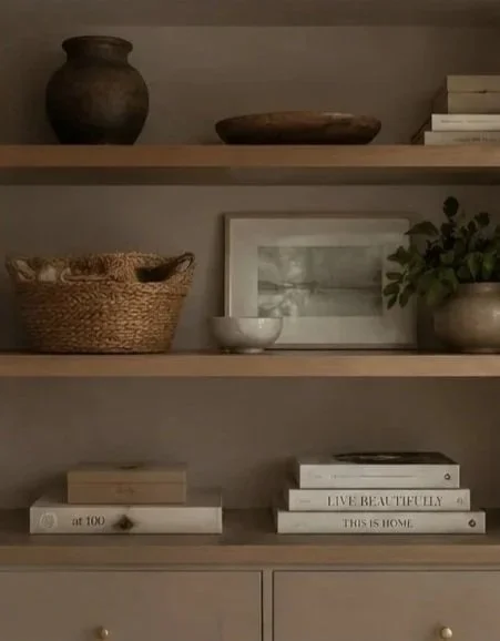 Interior shelf with decorative vases, a framed picture, a small bowl, a basket, and stacked books.