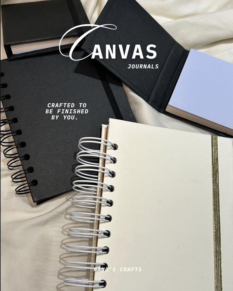 Various blank and lined notebooks with spiral and elastic bindings, some with black covers and others with white or blue covers, arranged on a light fabric surface.