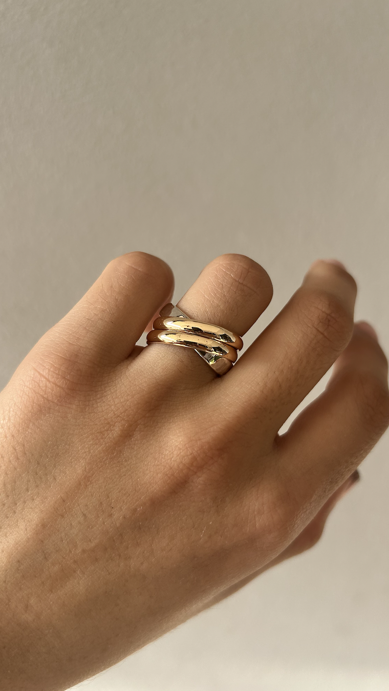 Close-up of a hand with a gold ring on the index finger against a plain background.
