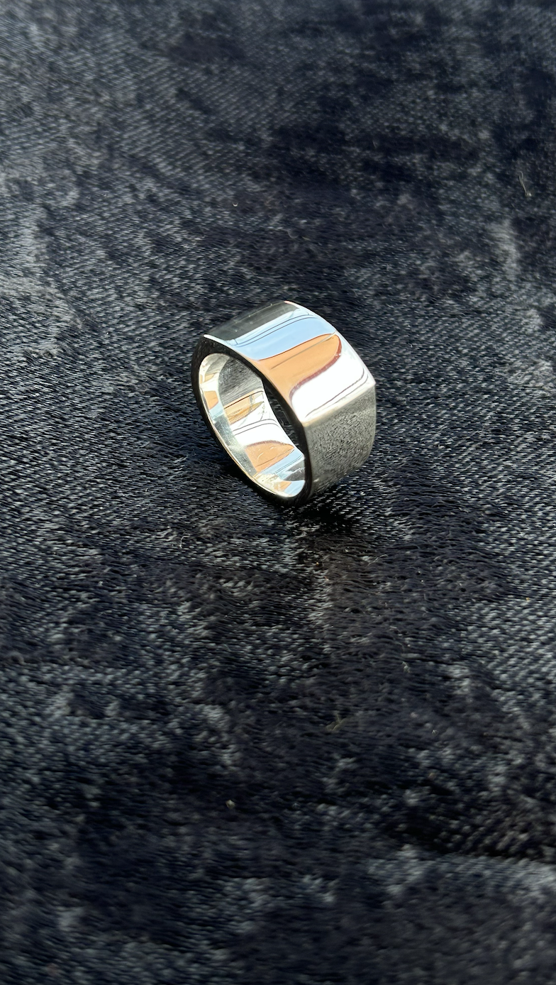 A shiny silver ring resting on a textured dark fabric background.