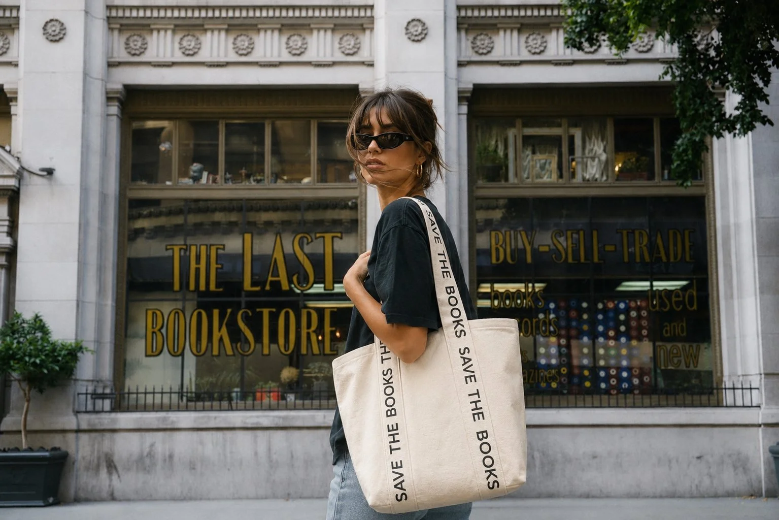A woman carrying a Save The Books tote bag outside The Last Bookstore to promote book rescue and literacy.