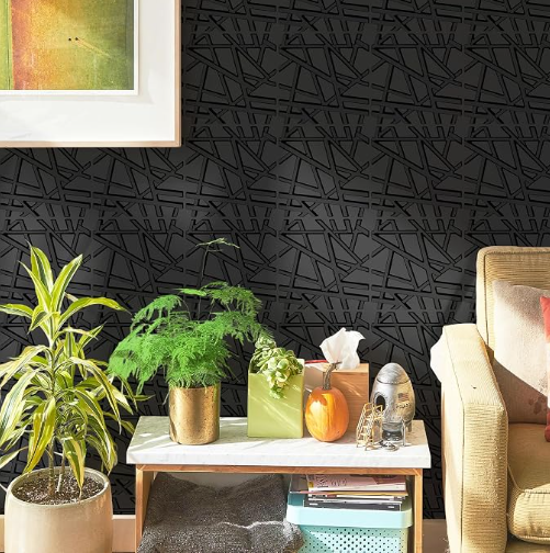 Living room corner with black textured wall, beige armchair with pink pillow, white marble side table with plants, tissues, decorative items, and storage boxes.