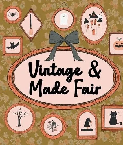 Decorative wall with framed vintage and Halloween-themed images, and a large sign that reads 'Vintage & Made Fair' with a gray bow at the top.