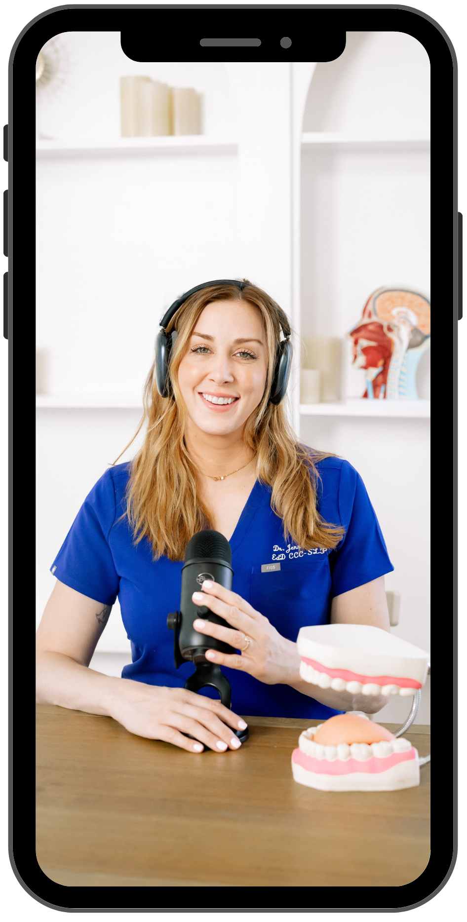 Dr. Jenn Moore speaking during a Next Level Motor training session with a podcast microphone and headphones.