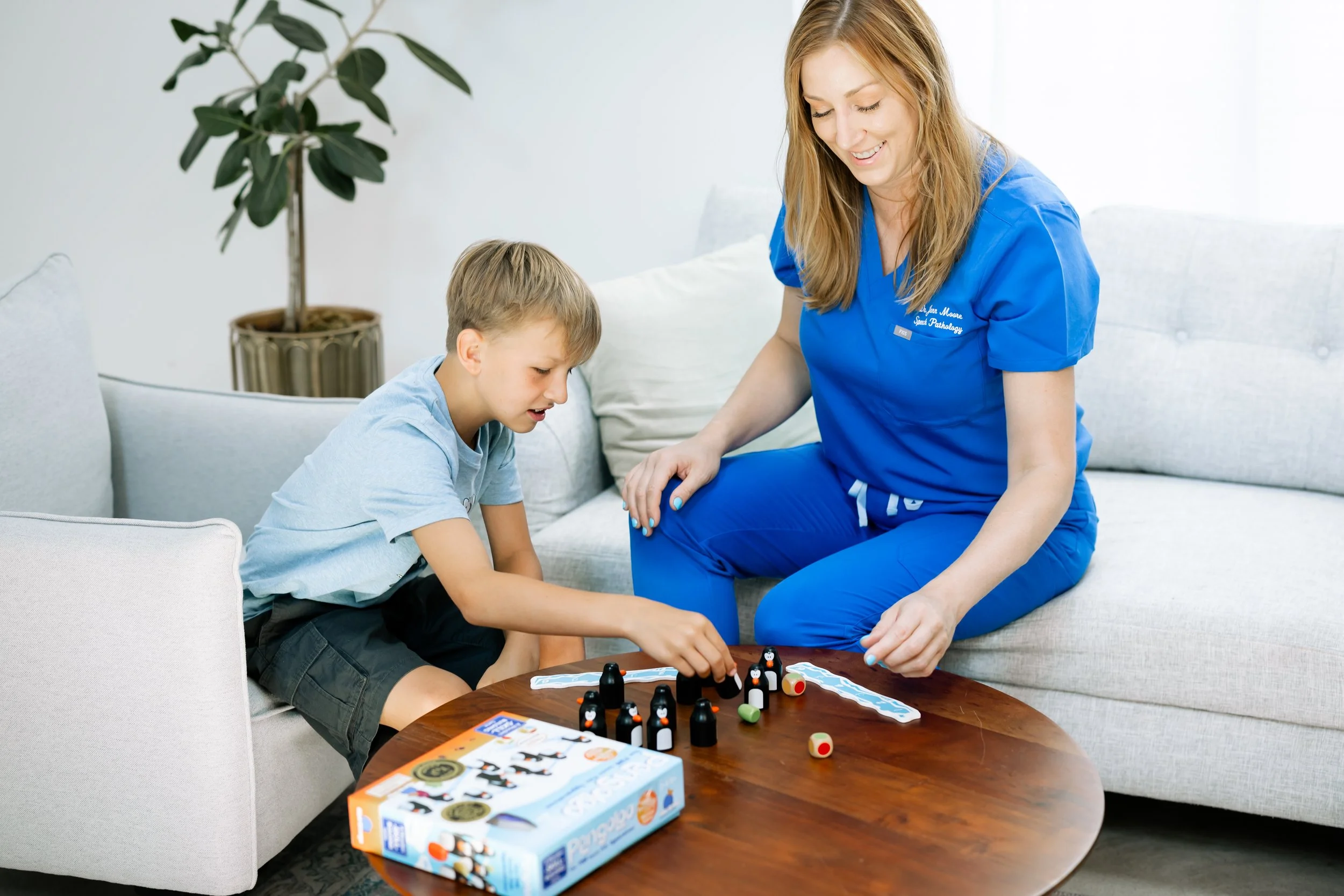 Dr. Jenn Moore providing play-based speech therapy with a child using games and hands-on activities.