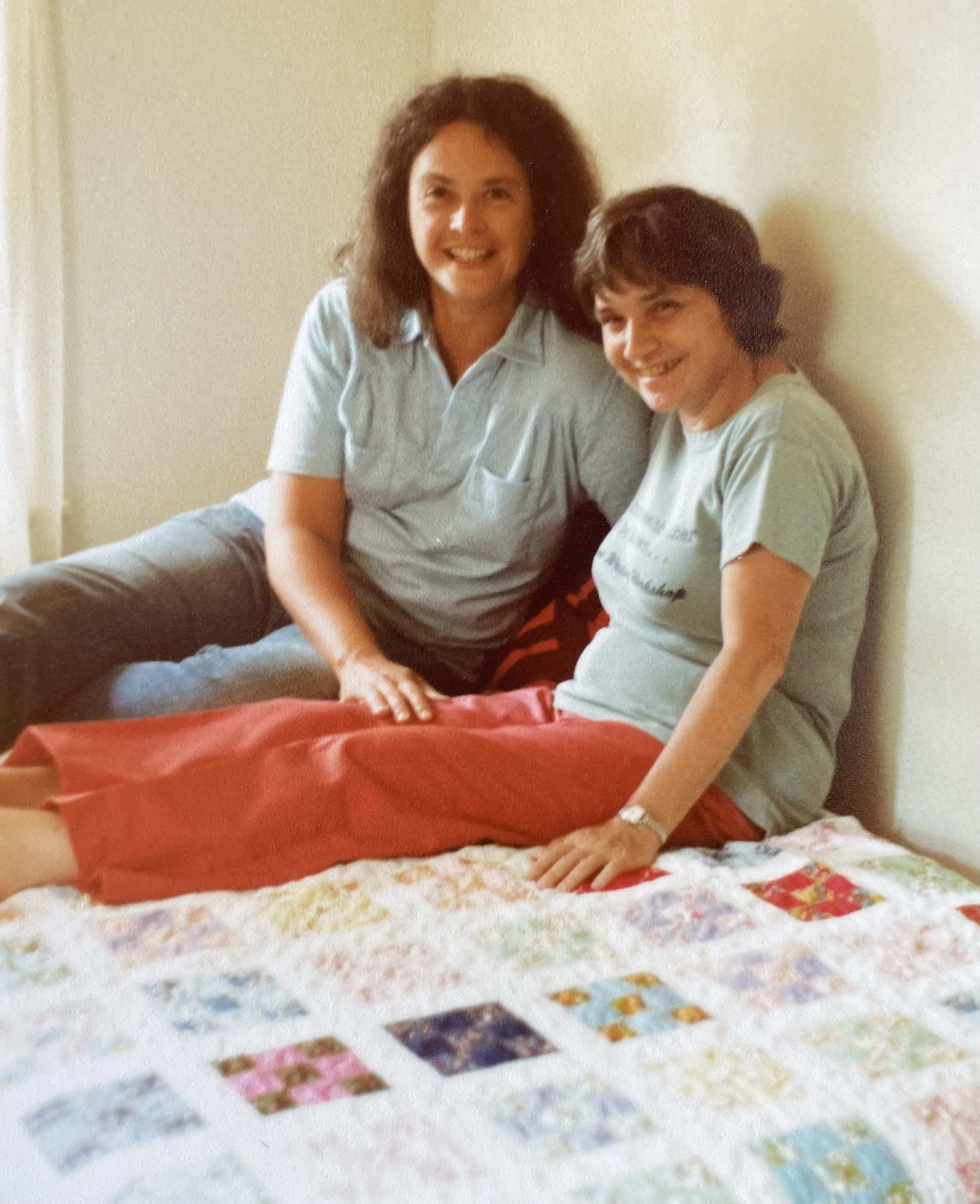 judith mcdaniel and adrienne rich sitting on quilt judith's grandmother made, smiling