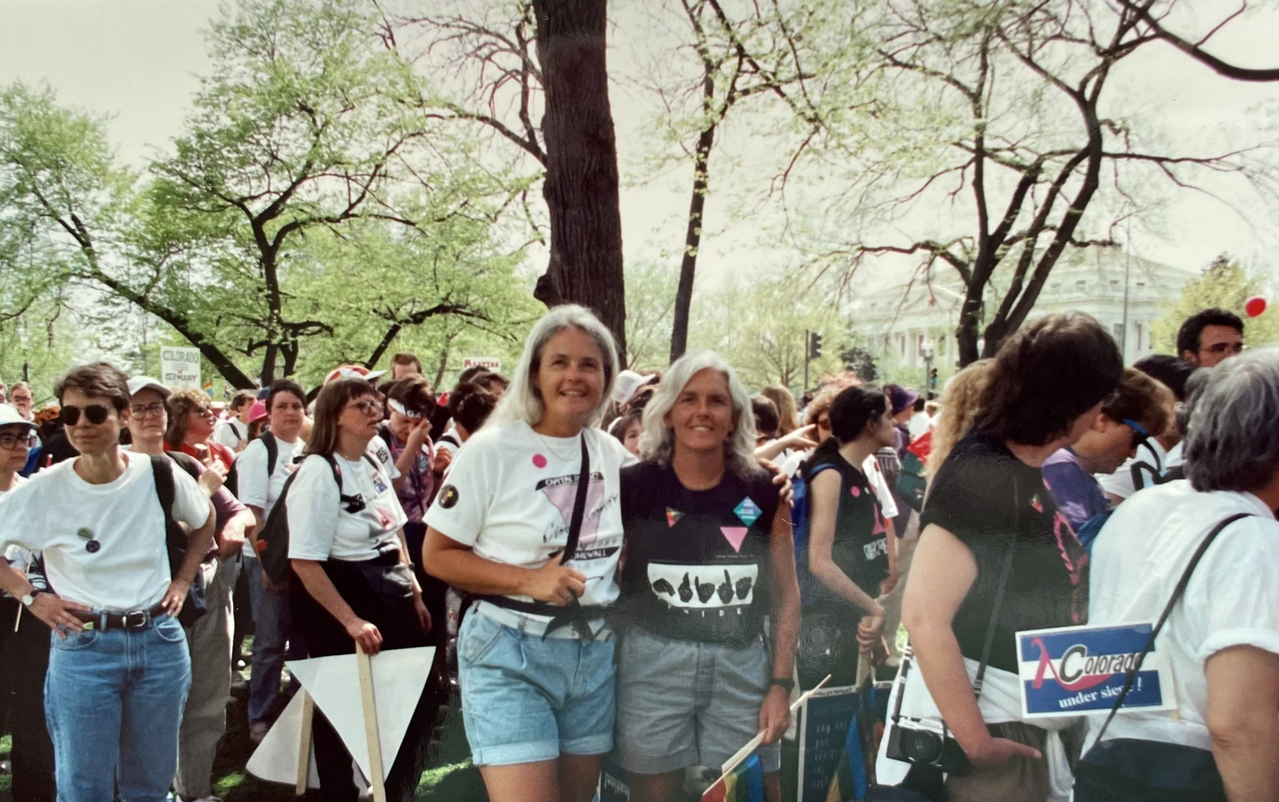 picture of judith mcdaniel wearing white shirt and her partner jan schwartz wearing black shirt with AIDS awareness pink triangle on t-shirts, protest from 1993