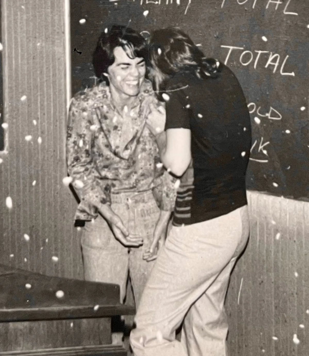 Black and white photo of Rita Mae Brown laughing and Elaine Nobel with confetti