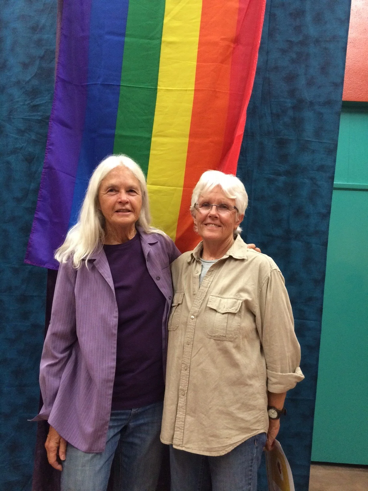 judith mcdaniel and partner jan schwartz in front of a pride flag