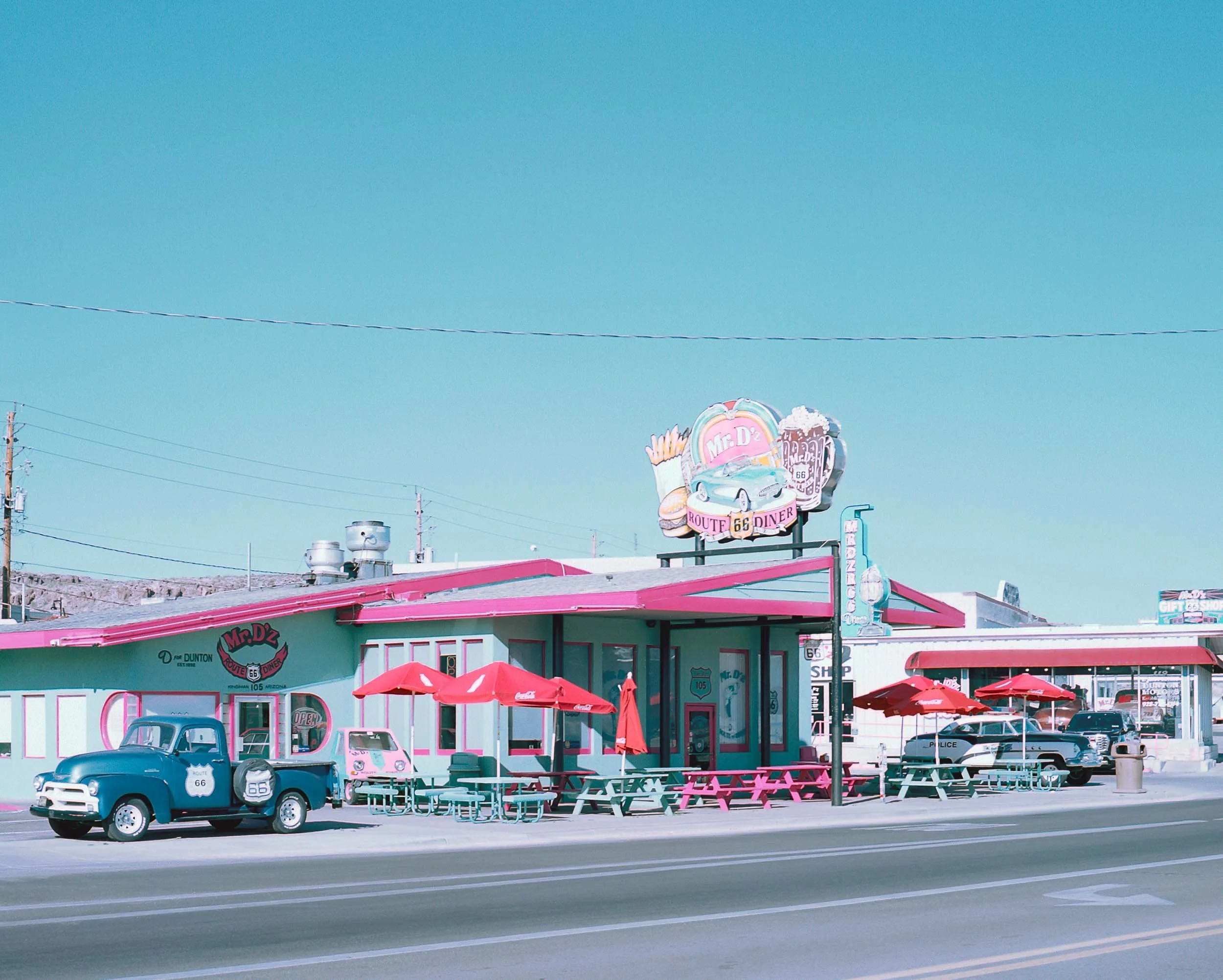 A vibrant pastel-colored diner with pink and turquoise accents along Route 66
