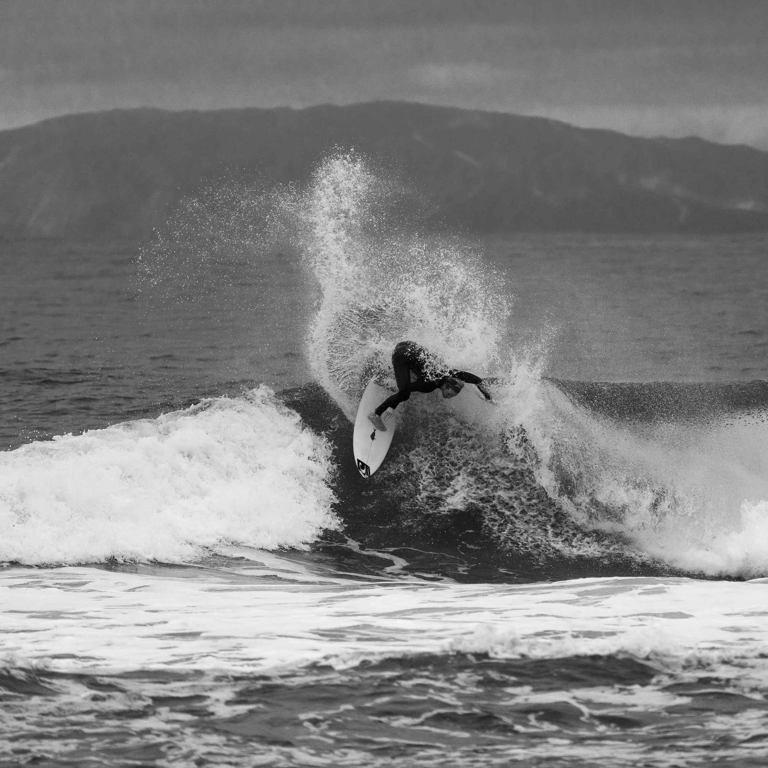 A person surfing on a surfboard black and white photo.