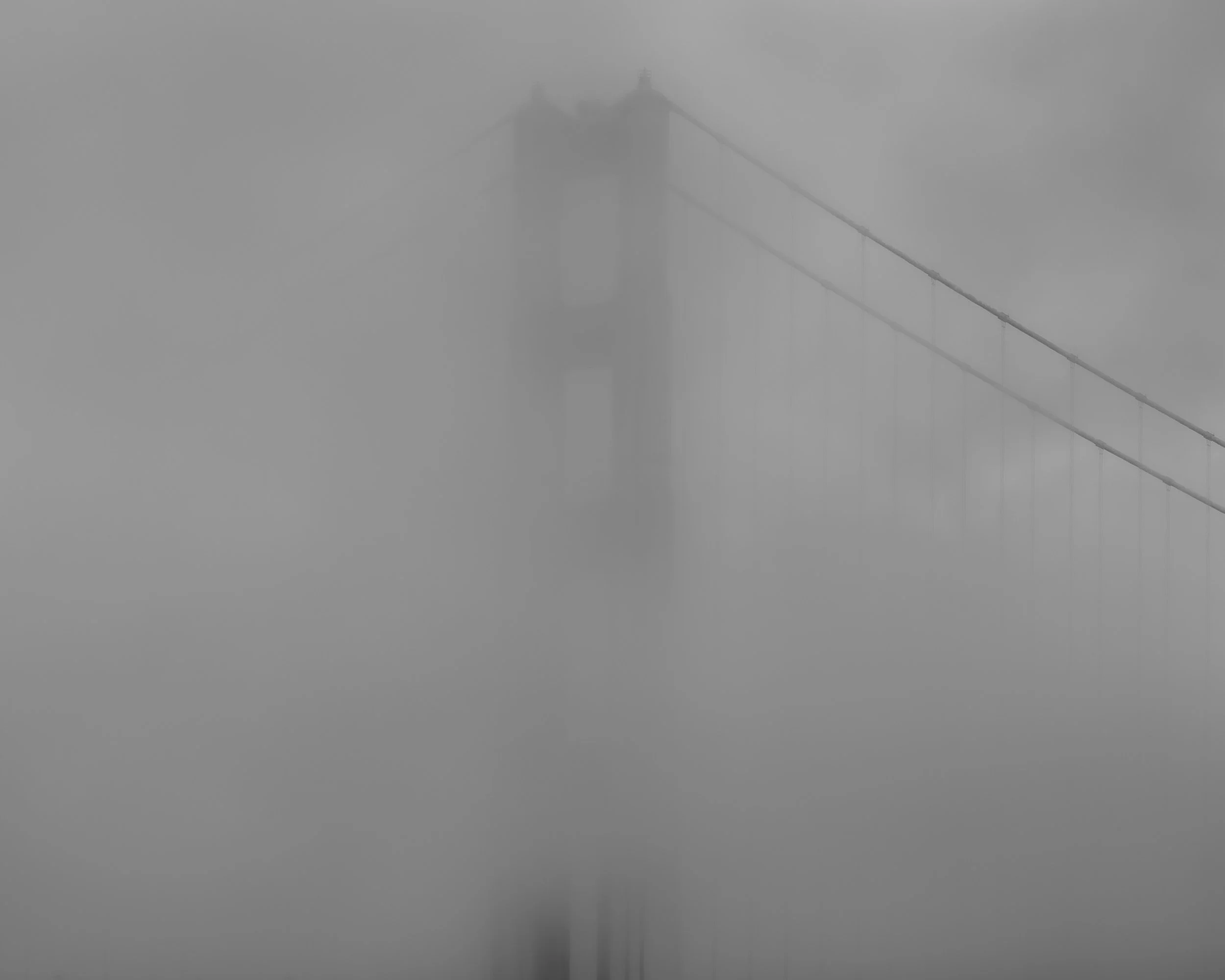 A foggy scene of the Golden Gate Bridge in San Francisco, California, with the bridge partially obscured by thick fog.