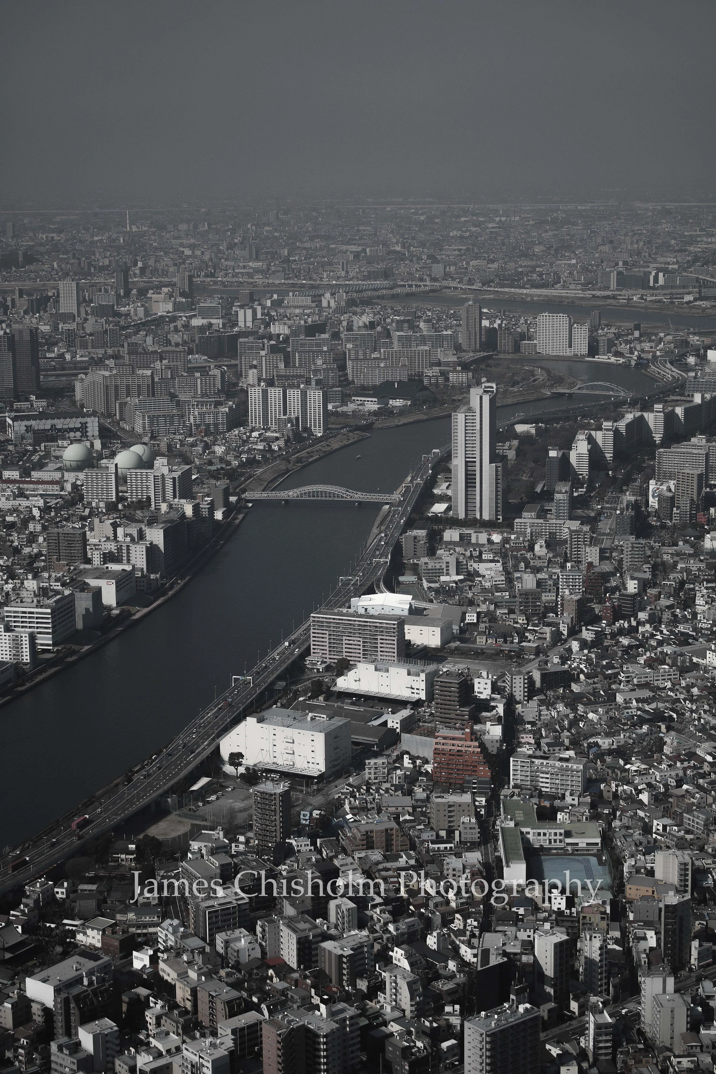 Aerial view of a city with numerous buildings, skyscrapers, and a river running through the city, with bridges crossing the river.