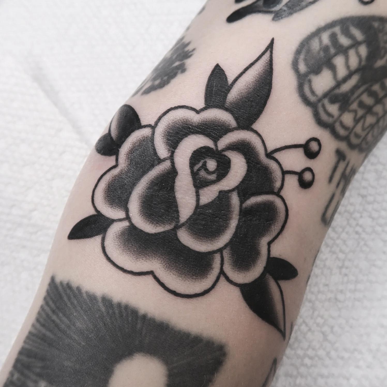Black and gray tattoo of a flower on a person's arm.