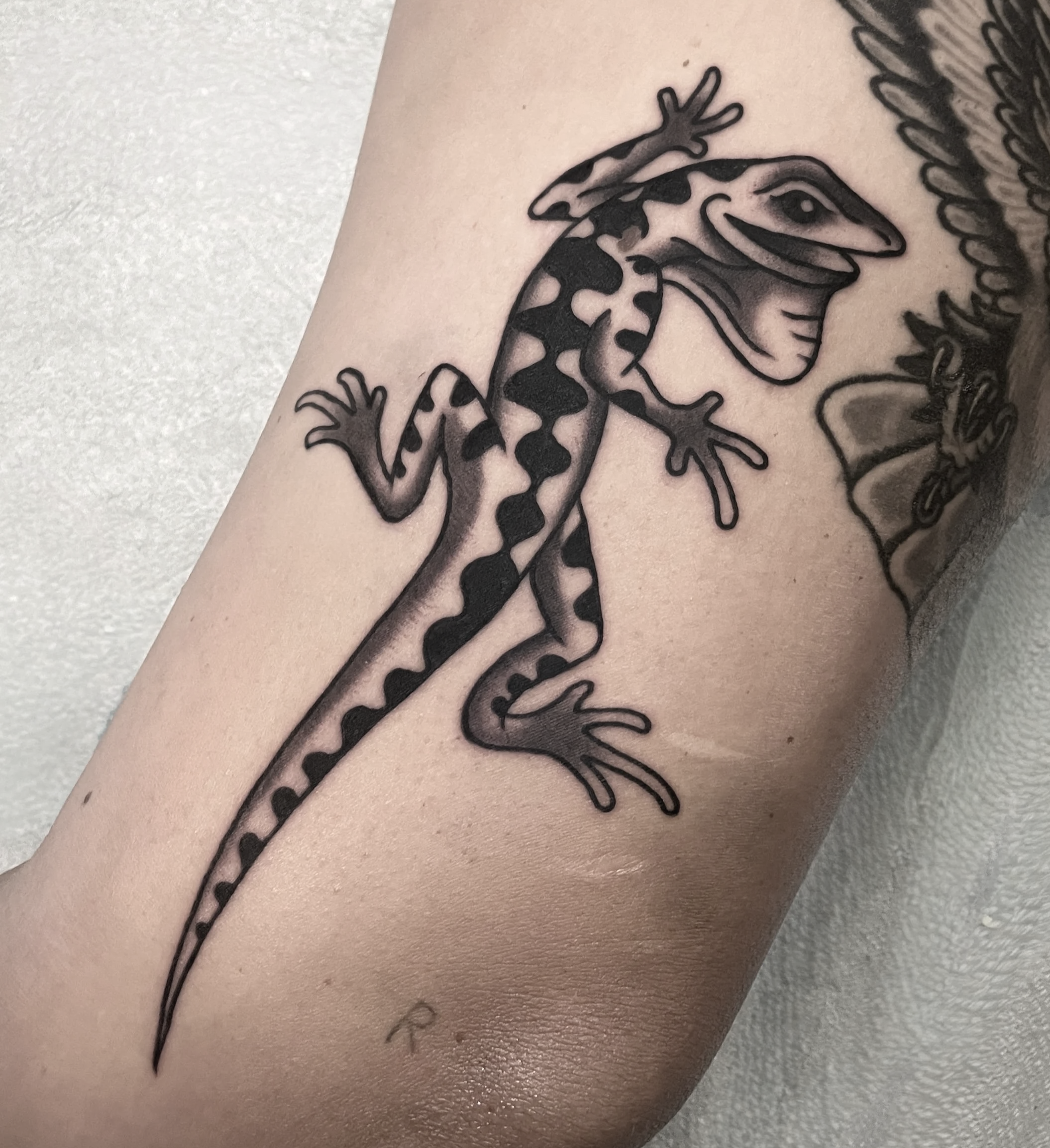 Close-up of a tattoo featuring a gecko with large spots.
