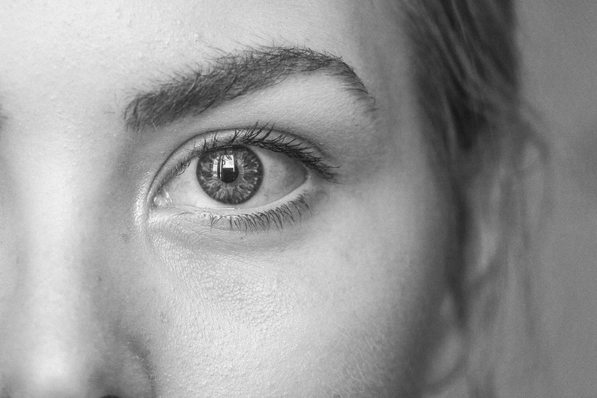 Close-up black and white photograph of a human eye with detailed iris and eyelashes.