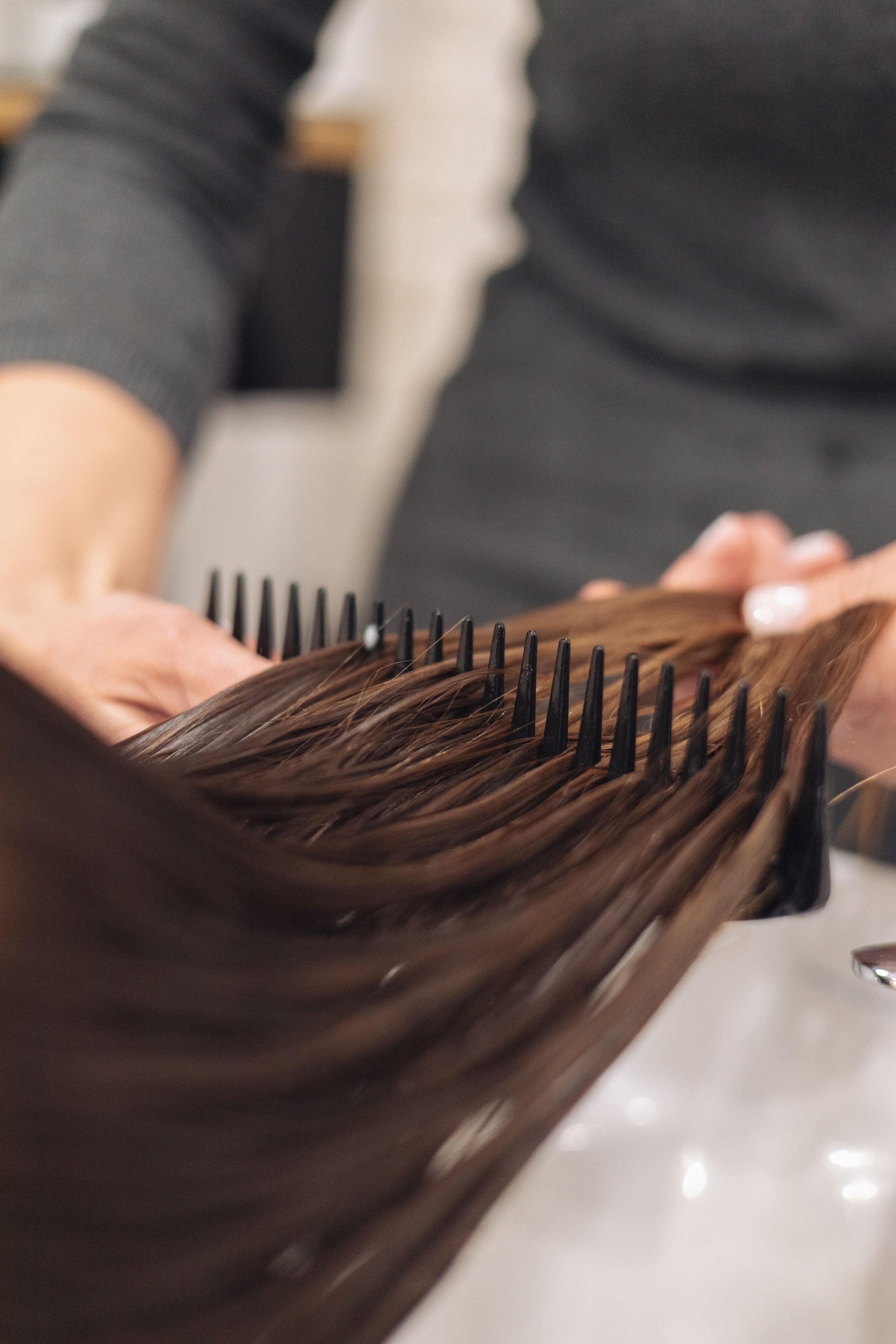 Close-up of a person's hair being styled with a hairbrush and hairbrush.