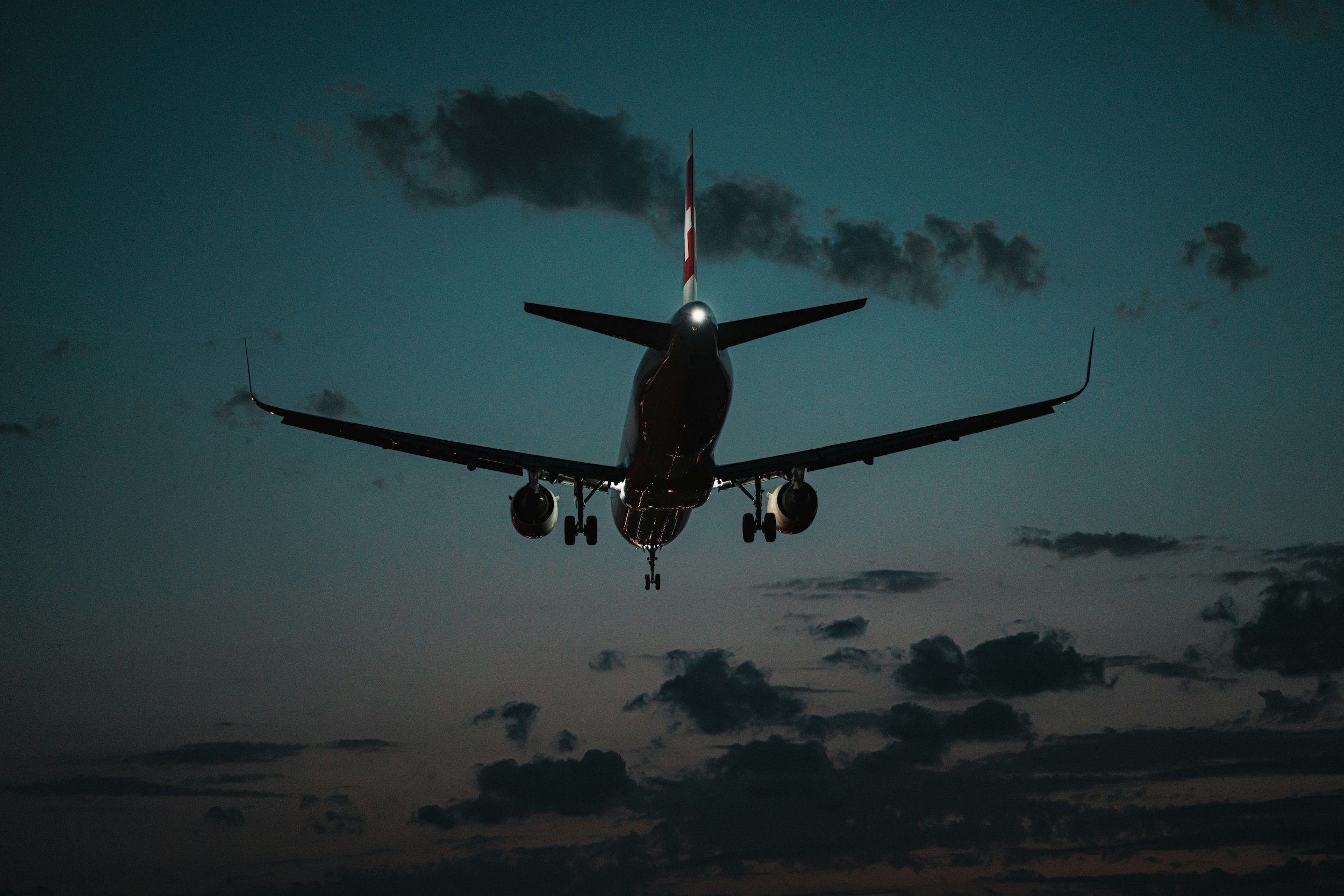 A commercial airplane flying low against a cloudy evening sky.