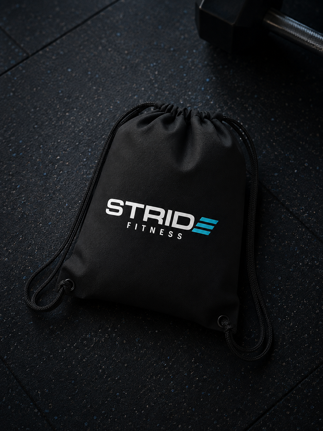 Black gym bag with 'STRIDE FITNESS' logo in white and blue on a rubber gym floor.