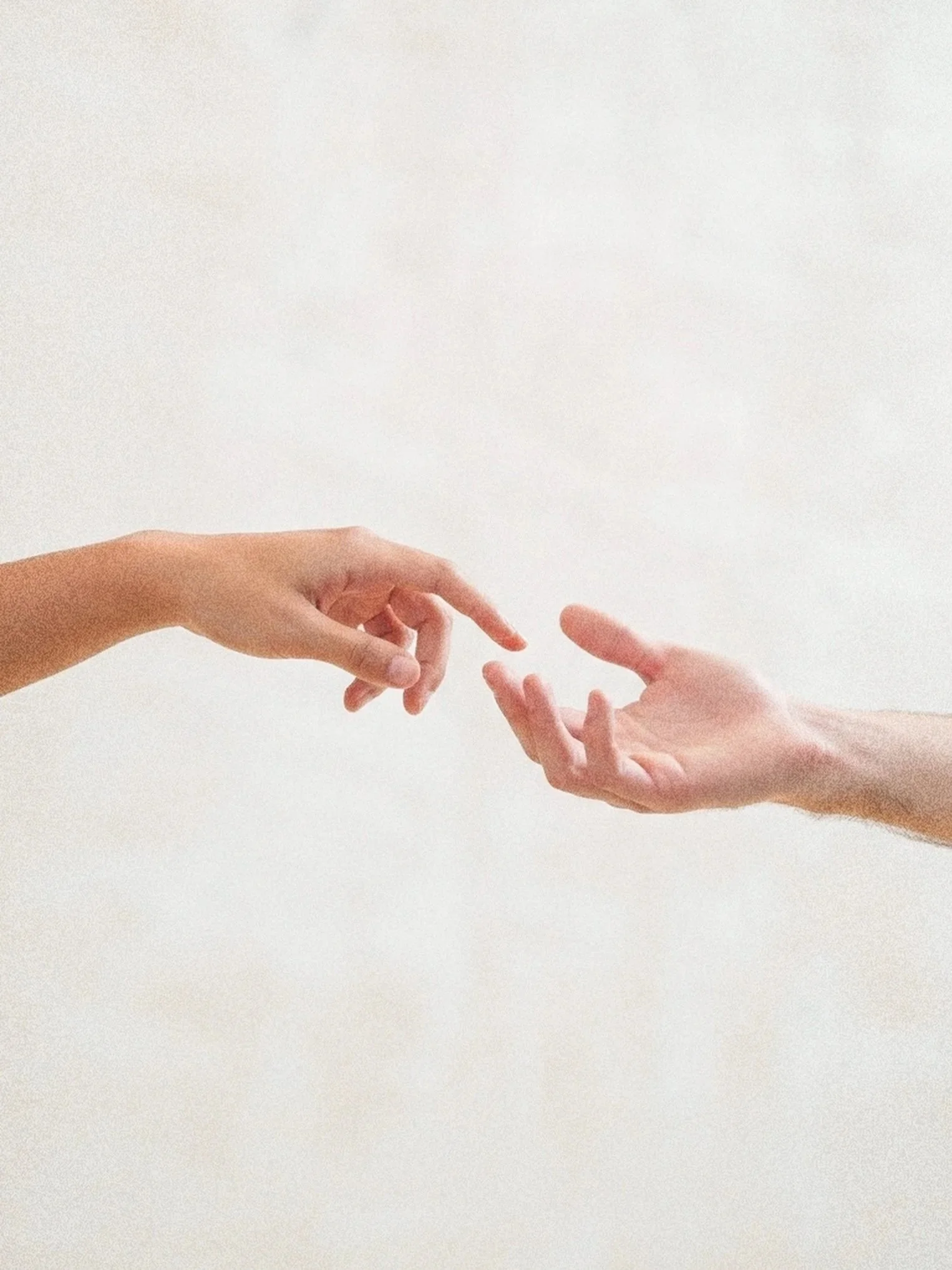 Close-up of two hands reaching and touching each other's fingertips against a plain light background.