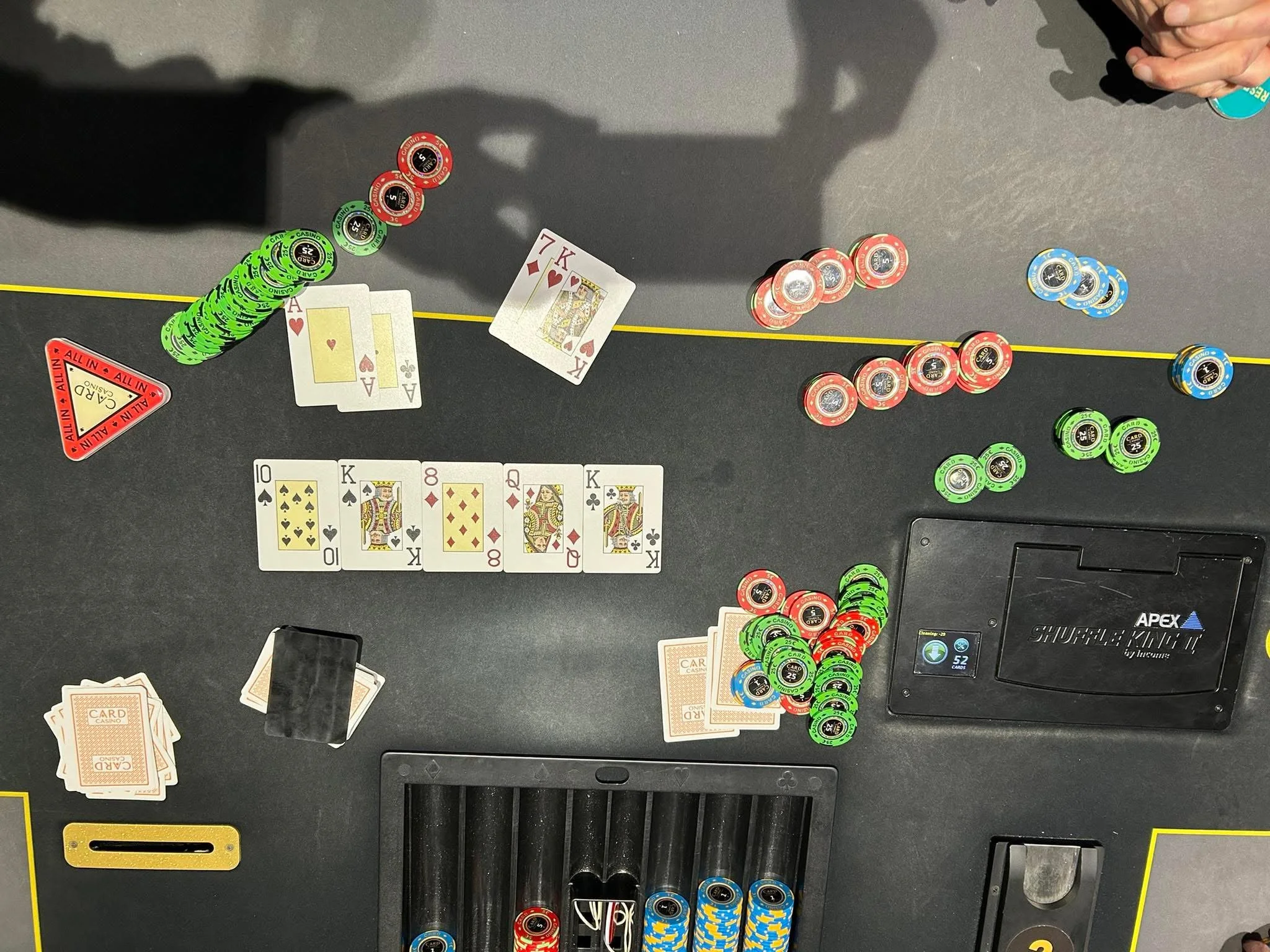 Playing cards and poker chips scattered on a casino table with a player's hand visible.