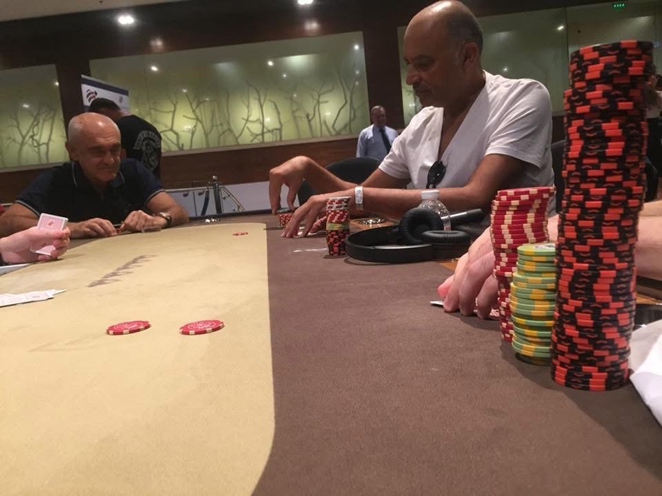 People playing poker at a casino table with stacks of poker chips.